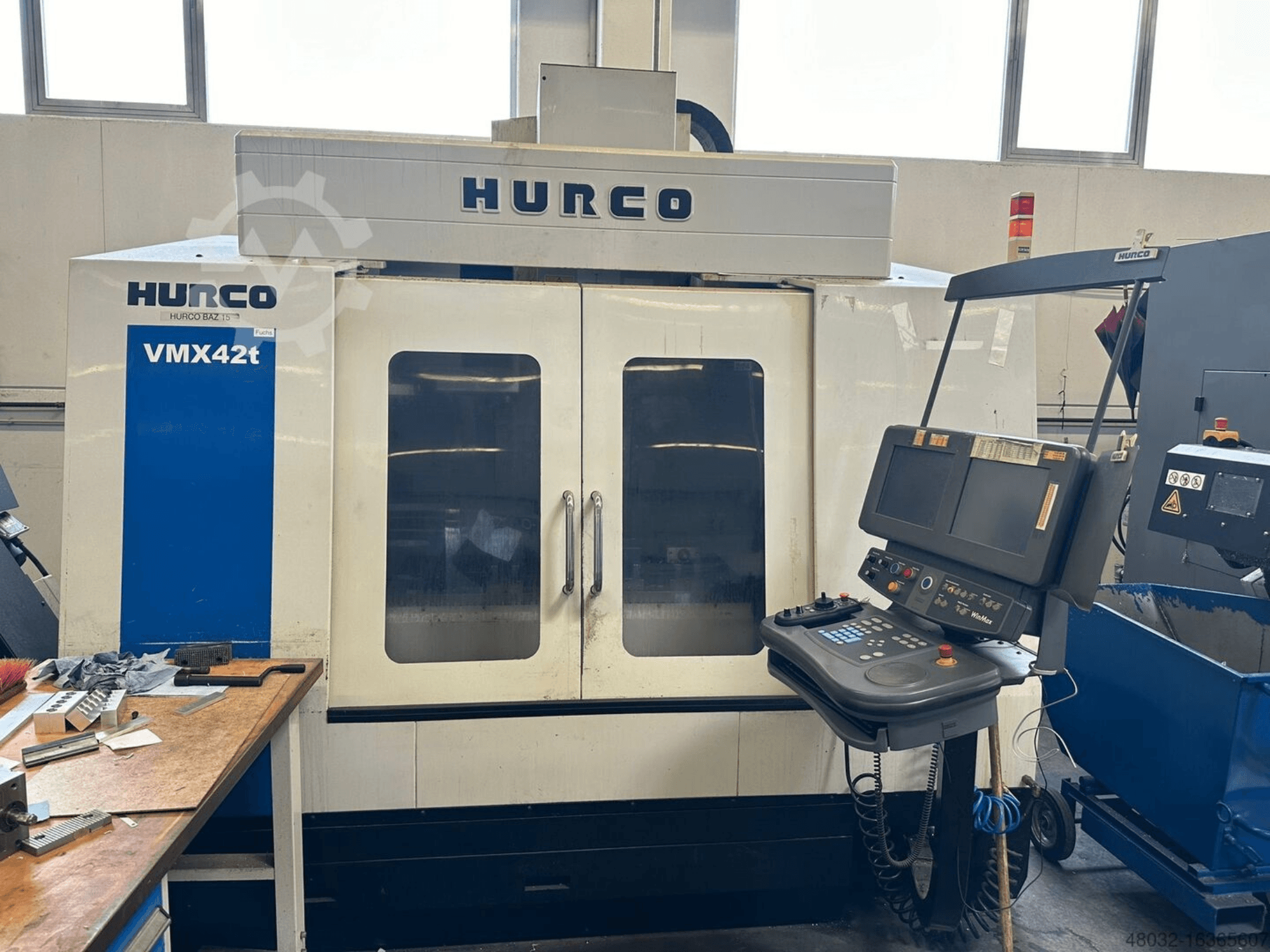 Centro di lavorazione verticale Hurco VMX42t, vista frontale, con pannello di controllo e interno visibile con utensili e pezzi in lavorazione.