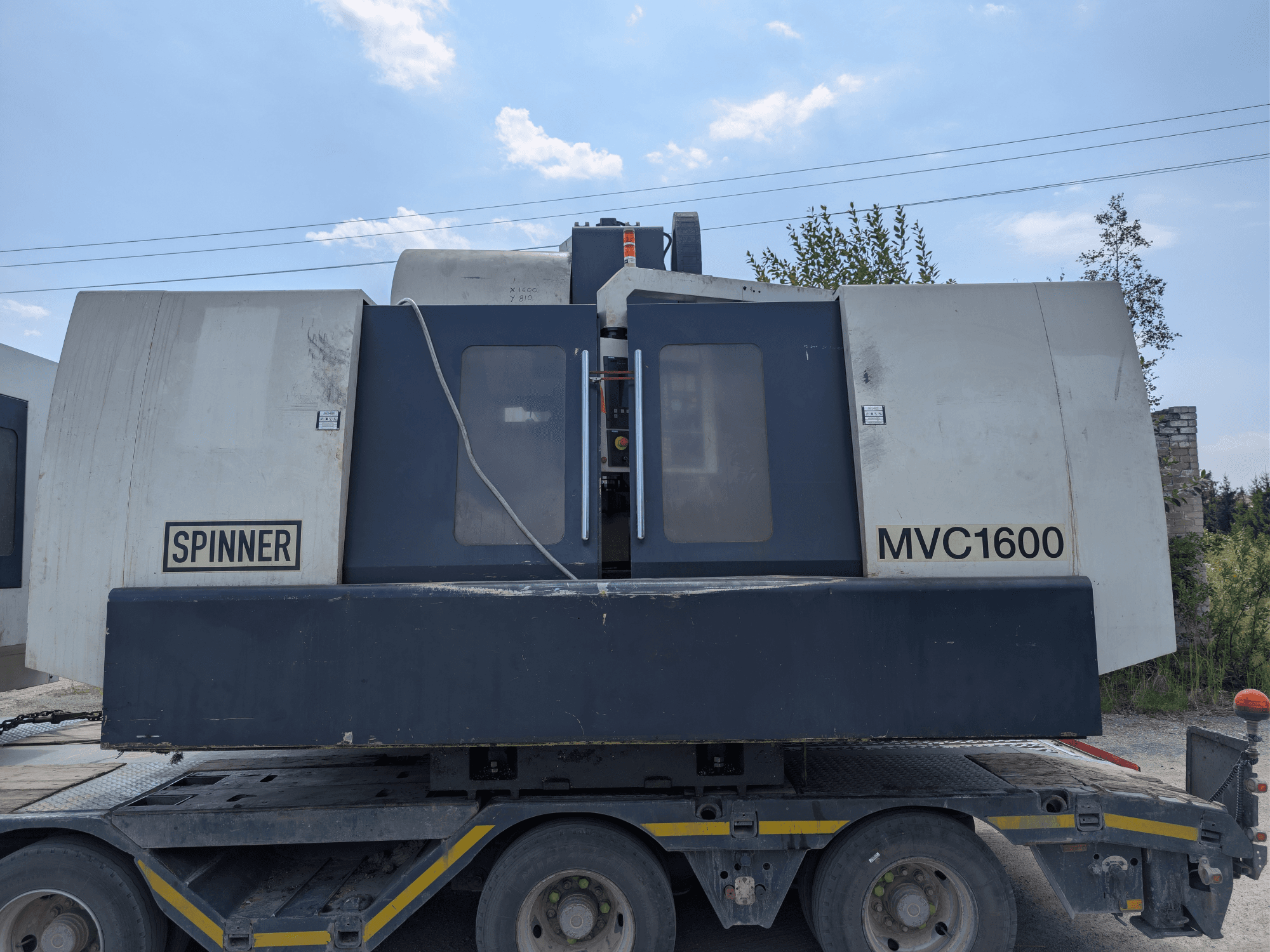 Centro di lavorazione verticale SPINNER MVC 1600, vista frontale su un camion, con in evidenza il marchio e l'ampia area di lavorazione.