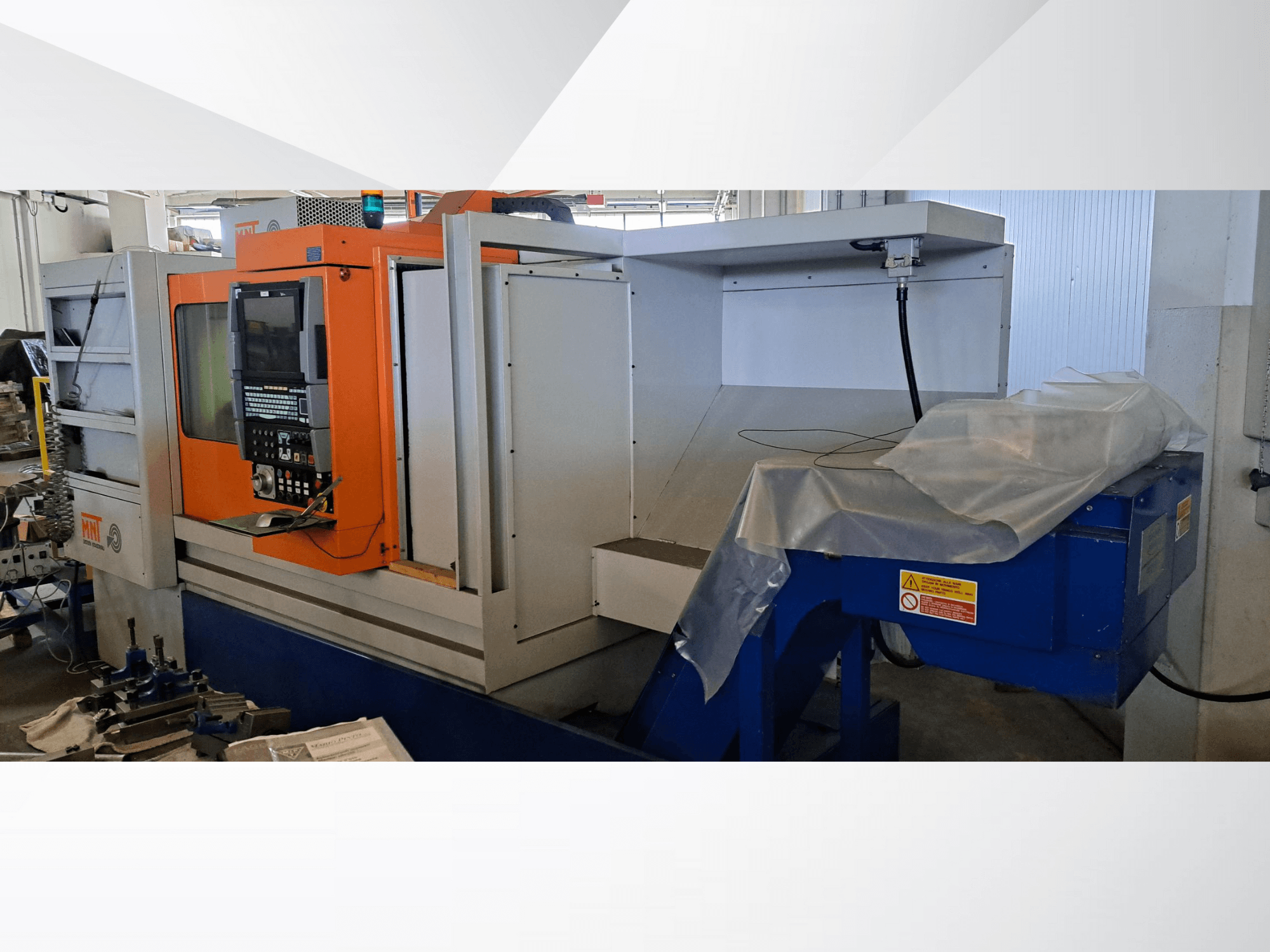 Macchina CNC MNT, vista frontale, con pannello di controllo arancione, ampia area di lavorazione e unità di smaltimento trucioli blu.