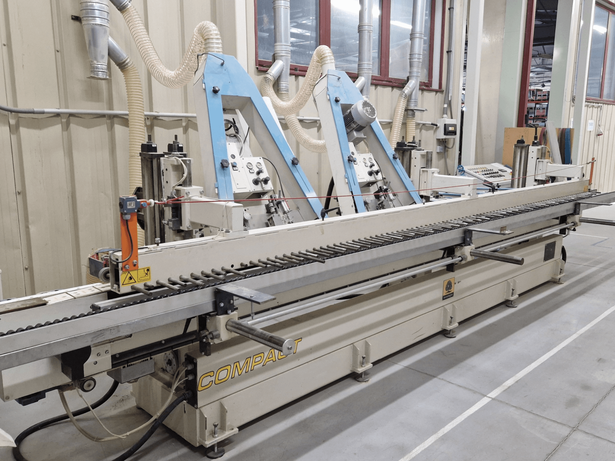 Levigatrice a nastro TECNOLEGNO COMPACT 52 in un'officina, che mostra il pannello di controllo e il meccanismo del nastro abrasivo da una vista laterale.