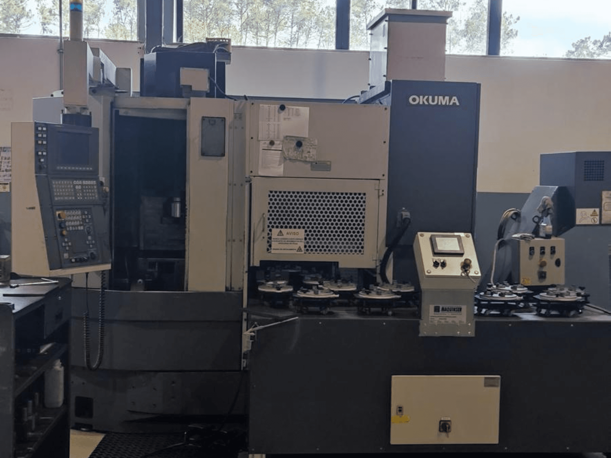 Tornio verticale Okuma LVT300 in vista frontale, con pannello di controllo, portautensili e area di lavorazione.