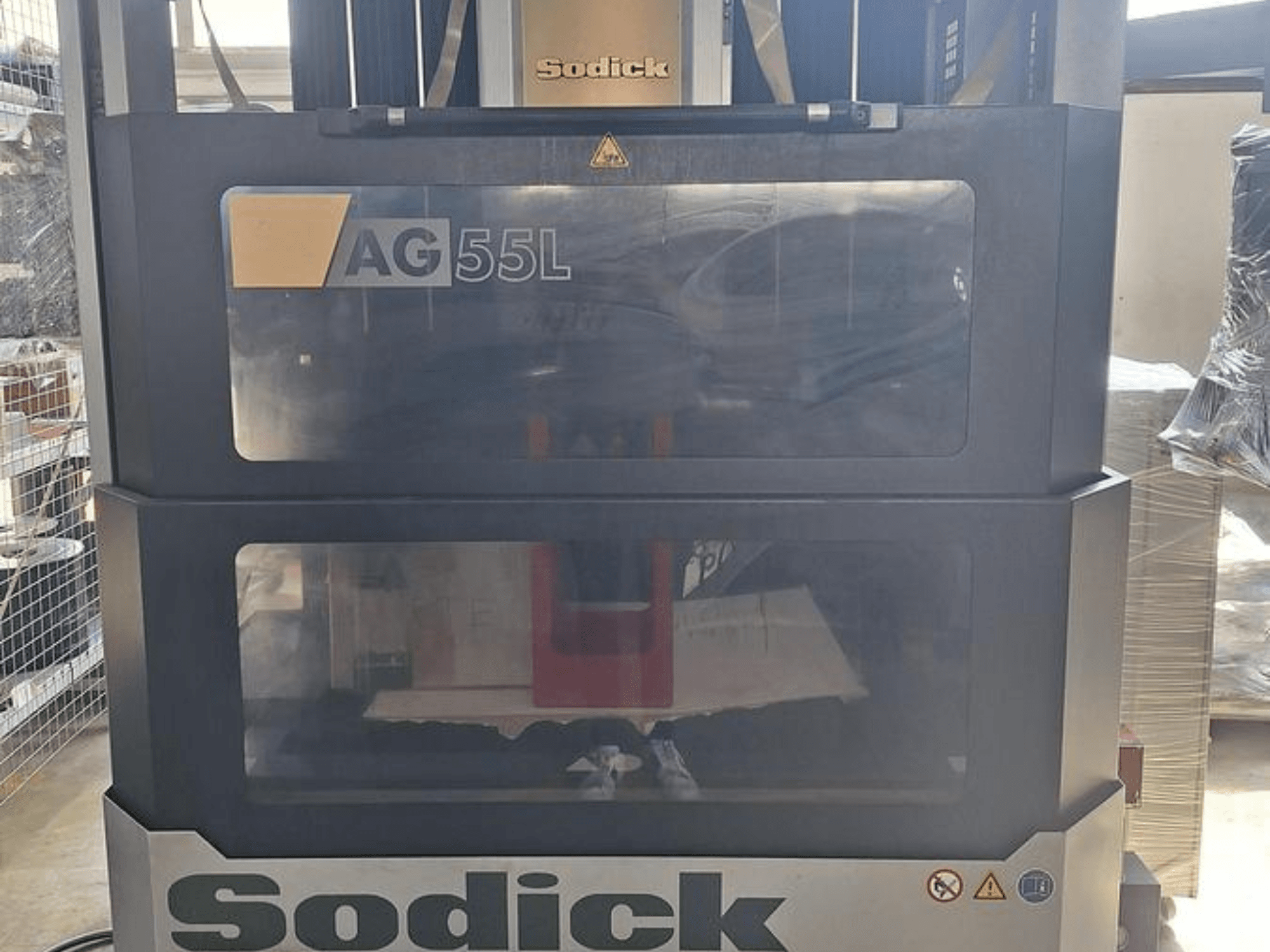 Macchina per elettroerosione a tuffo Sodick AG 55L, vista frontale con comandi visibili attraverso pannelli trasparenti, che mostrano l'area di lavoro interna.