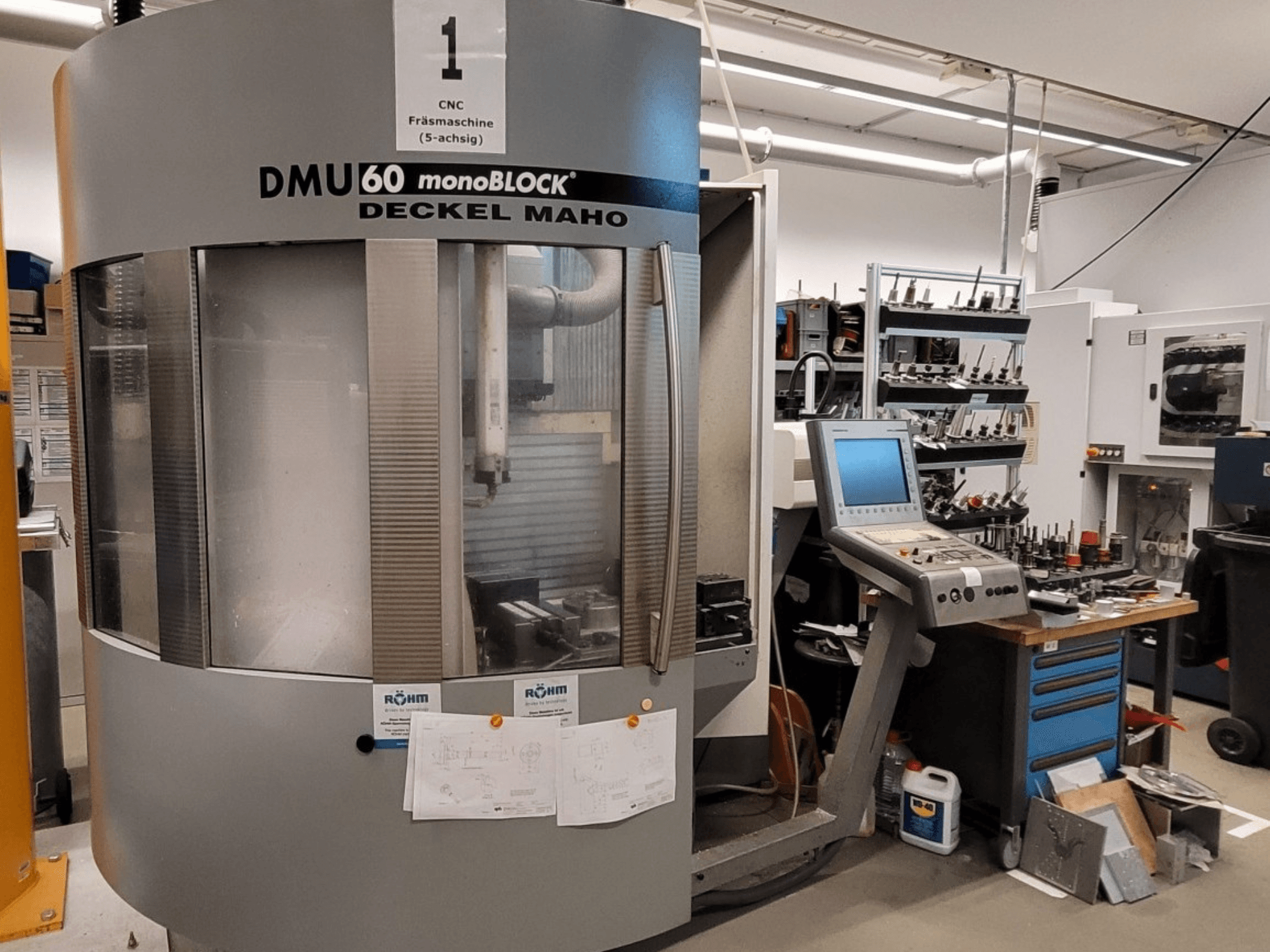 Fresatrice CNC DECKEL MAHO DMU 60 monoBLOCK in vista frontale, con accanto il pannello di controllo e il magazzino utensili.