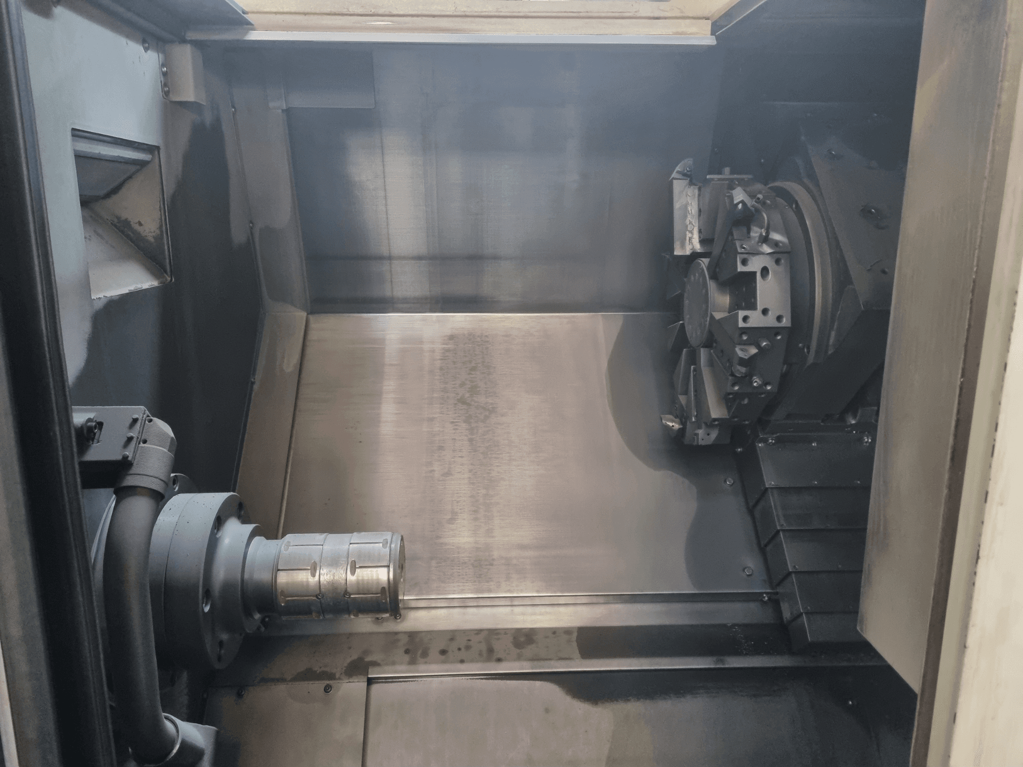 Vista interna di una macchina CNC che mostra l'area di lavoro in metallo, il portautensili e il mandrino; sottolinea l'ingegneria di precisione.