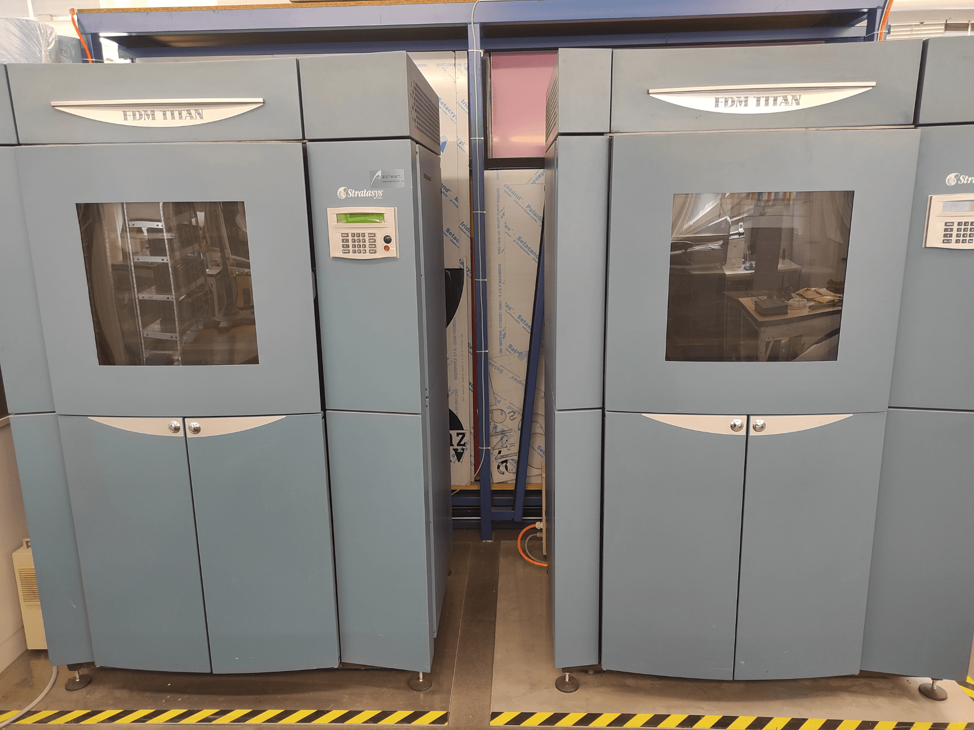 Stampante 3D FDM TitanTI di Stratasys, vista frontale, con doppio sportello e pannello di controllo, collocata in un ambiente industriale.