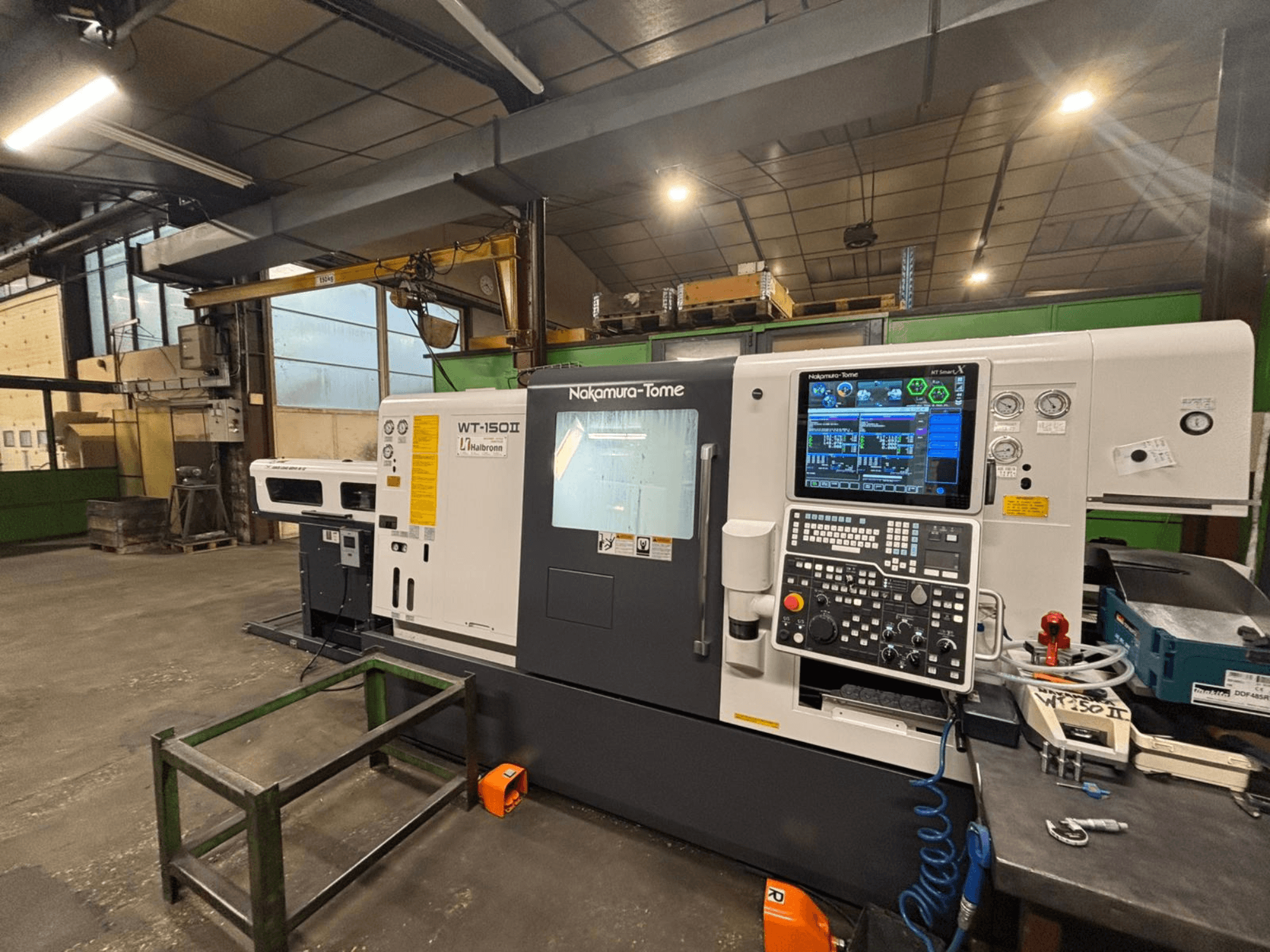 Macchina Nakamura-Tome WT-150II, vista frontale, con pannello di controllo e utensili visibili su un banco di lavoro in un'officina.