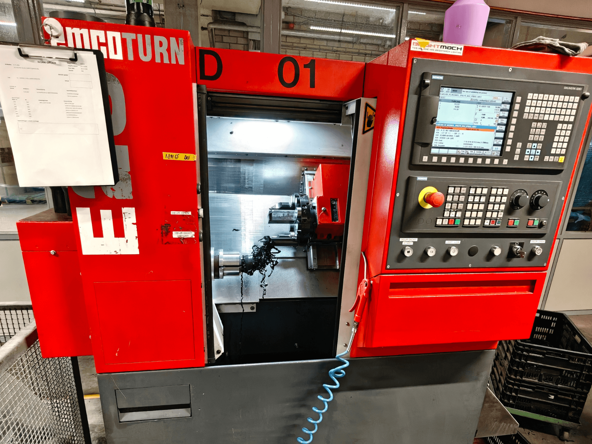 Vista frontale del tornio orizzontale EMCO TURN E25, con comandi operativi, portautensili e area di lavoro con trucioli.