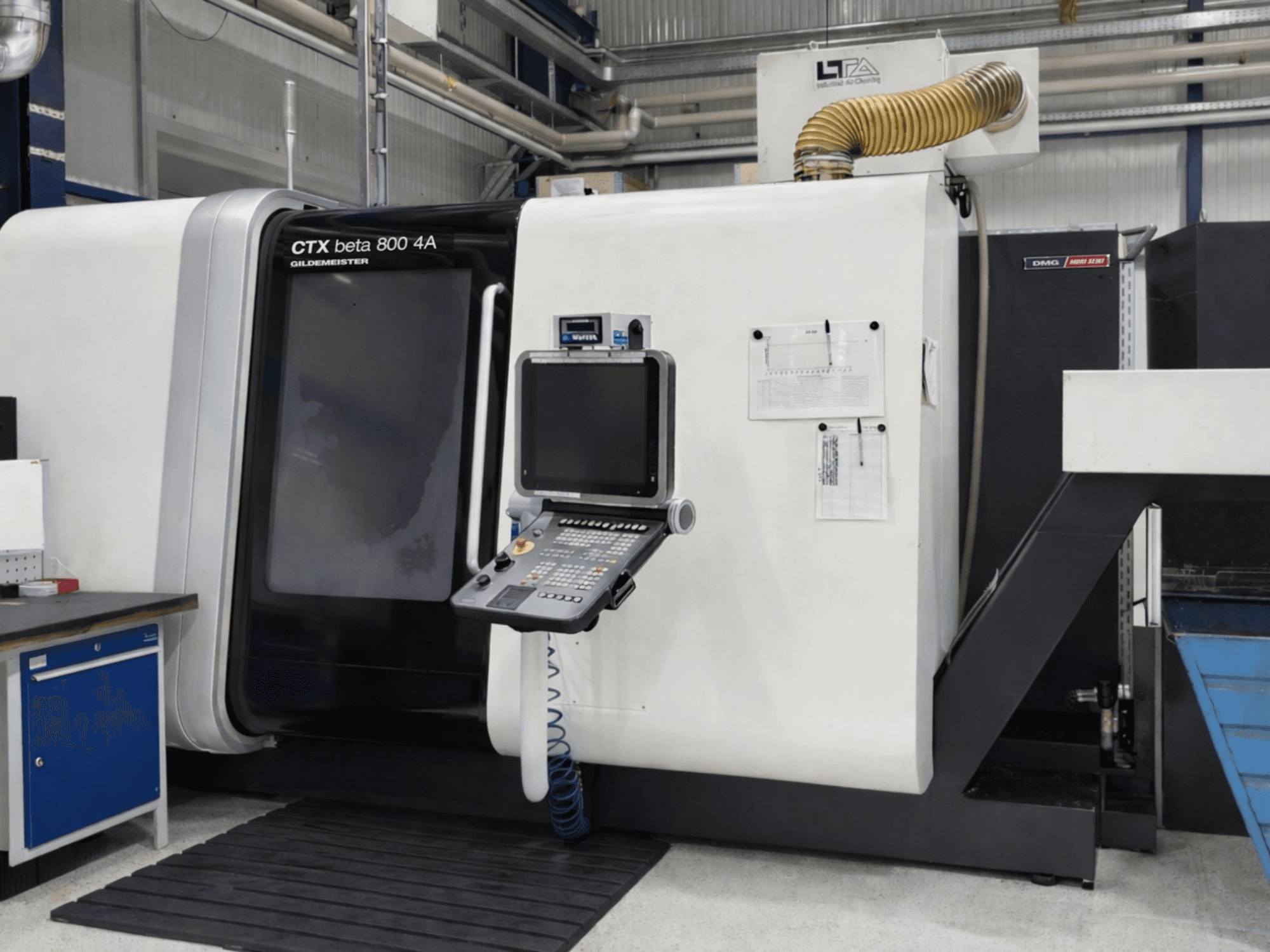 Tornio multimandrino DMG CTX beta 800 4A, vista frontale, con pannello di controllo e documentazione operativa in primo piano.