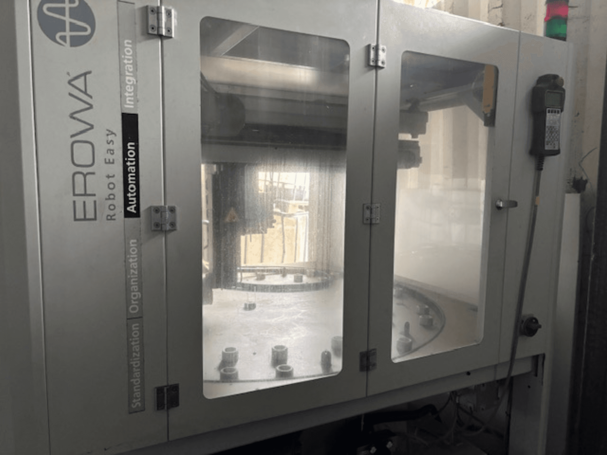 Vista frontale di EROWA Robot Easy Automation; presenta porte trasparenti, componenti di automazione visibili e pannello di controllo.