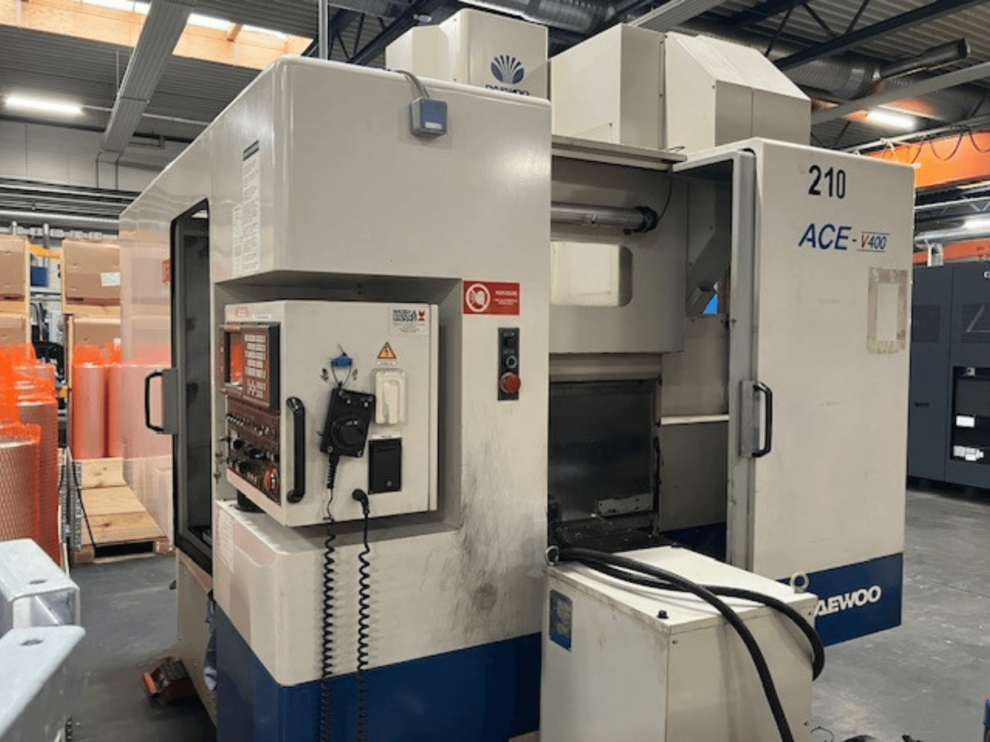 Macchina CNC Daewoo ACE-V400 in vista laterale, con pannello di controllo, serbatoio del refrigerante e area di lavoro aperta.