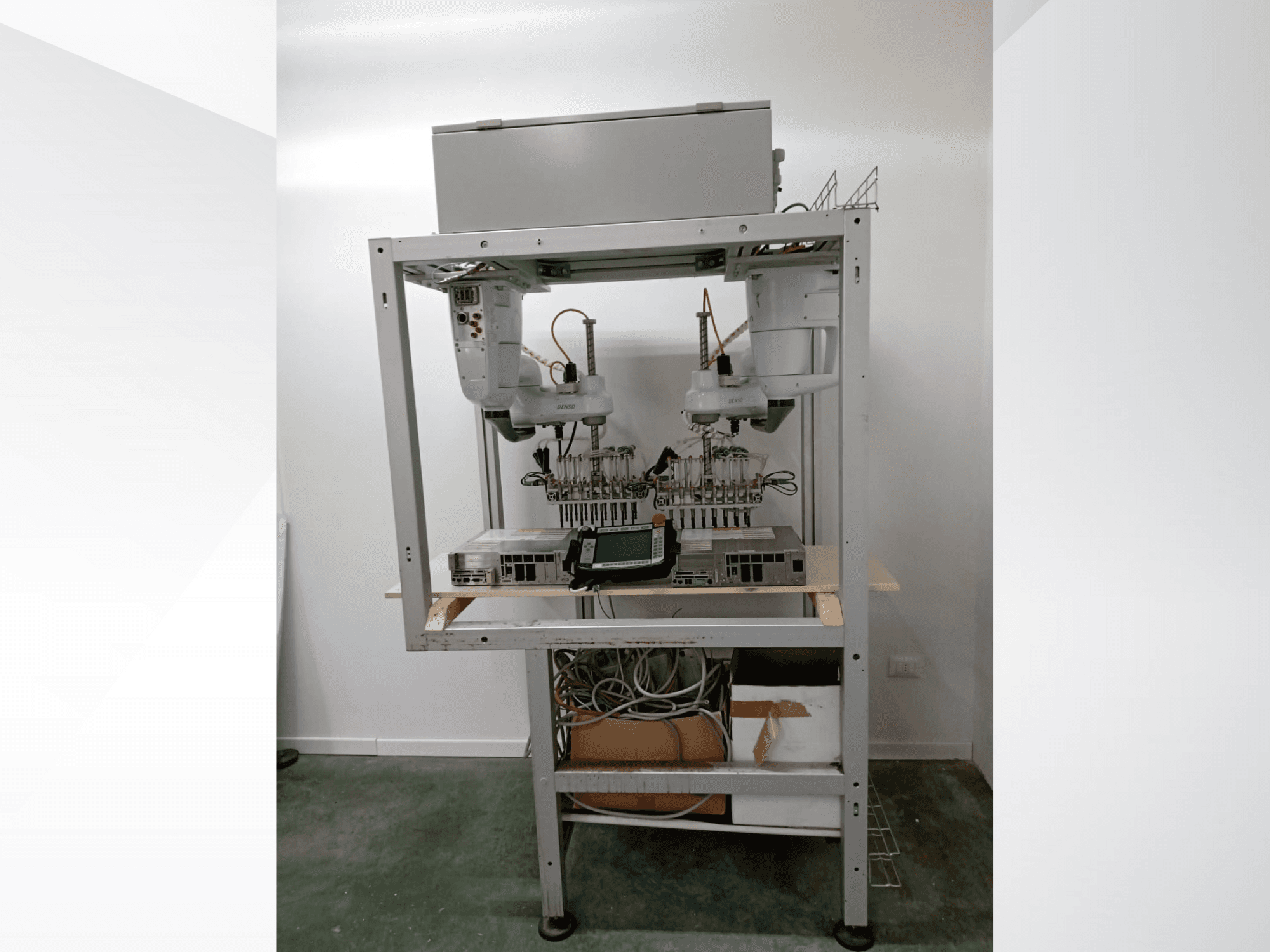 Postazione robotizzata automatizzata con doppio braccio, unità di visualizzazione ed elettronica su una struttura metallica, vista frontale, configurazione tecnologica avanzata.