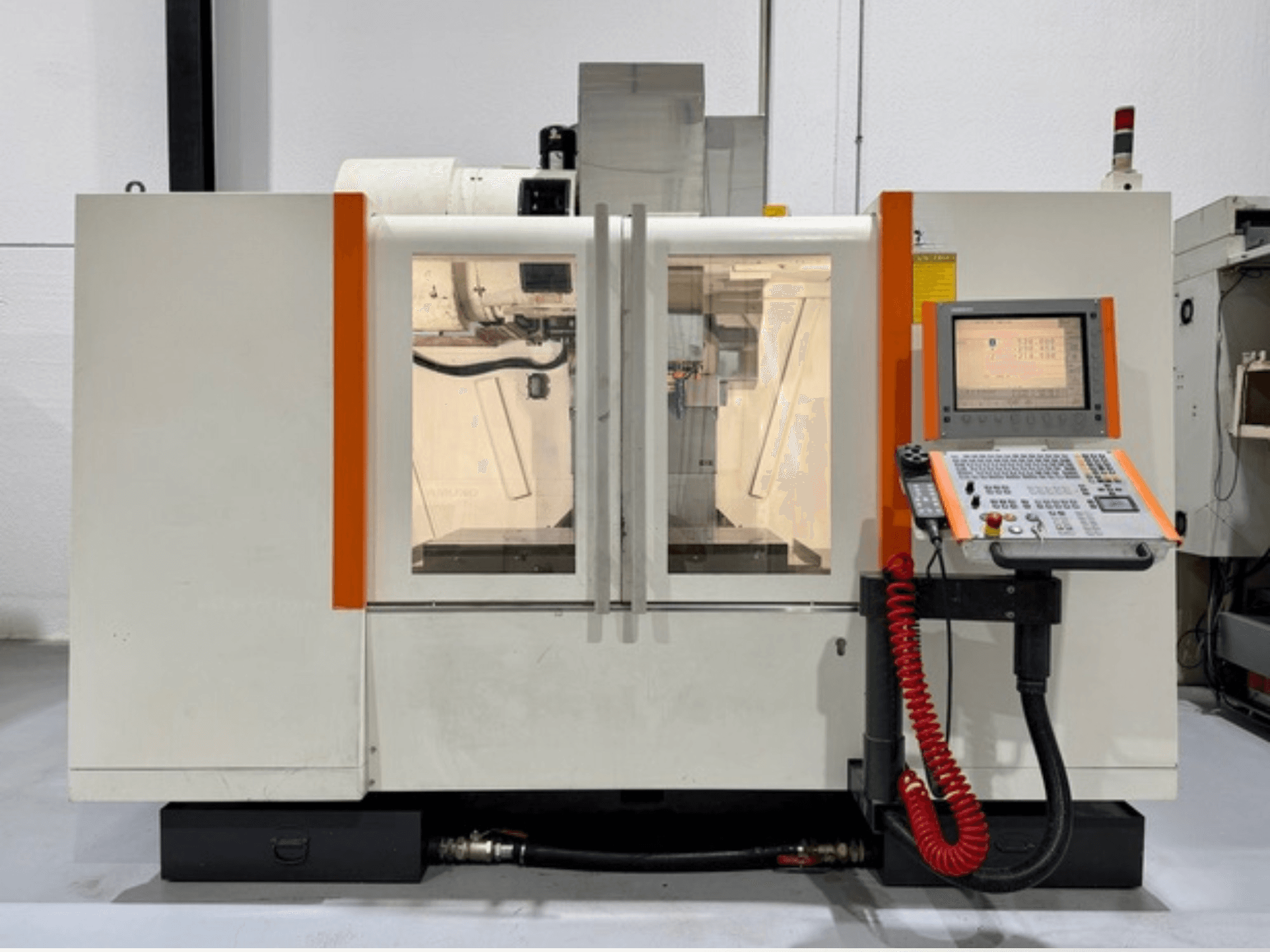 Macchina CNC con accenti arancioni, vista frontale. Include pannello di controllo e lavorazioni interne visibili.