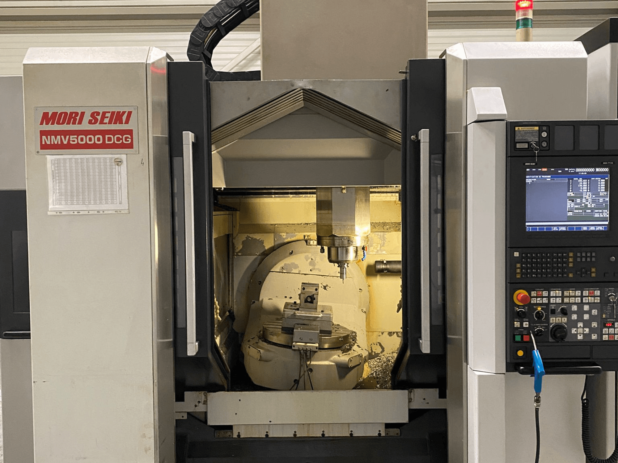 Centro di lavoro universale MORI SEIKI NMV 5000DCG, vista frontale che mostra il pannello di controllo e l'area di lavorazione interna.