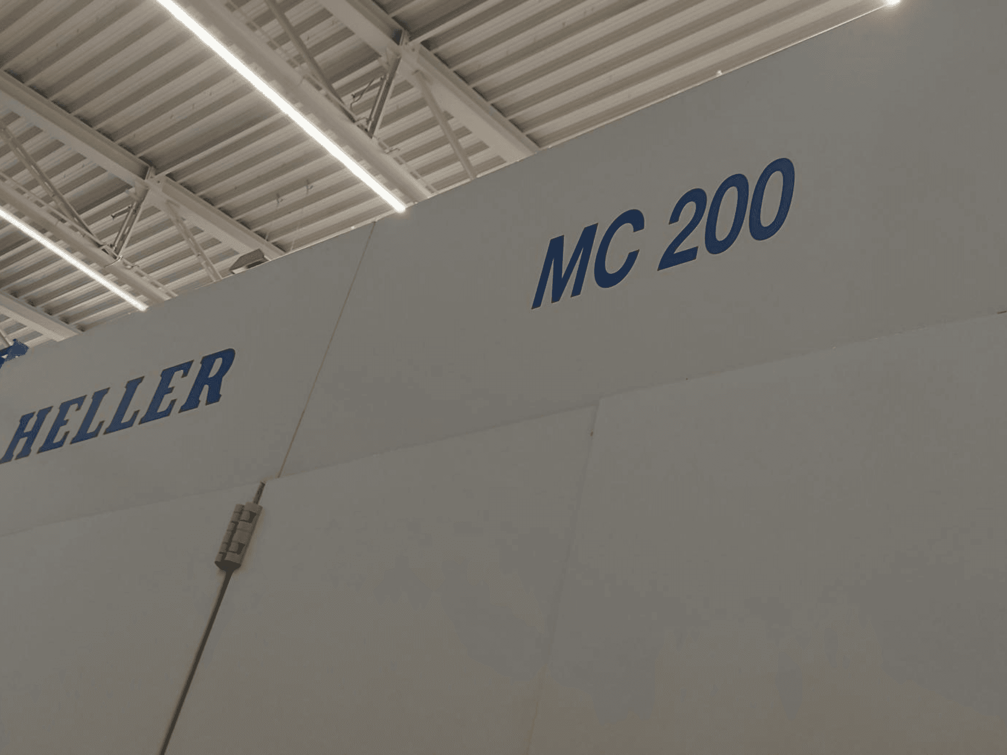 Centro di lavoro orizzontale Heller MC 200, visto di lato, con marchio e modello in caratteri blu su superficie bianca.