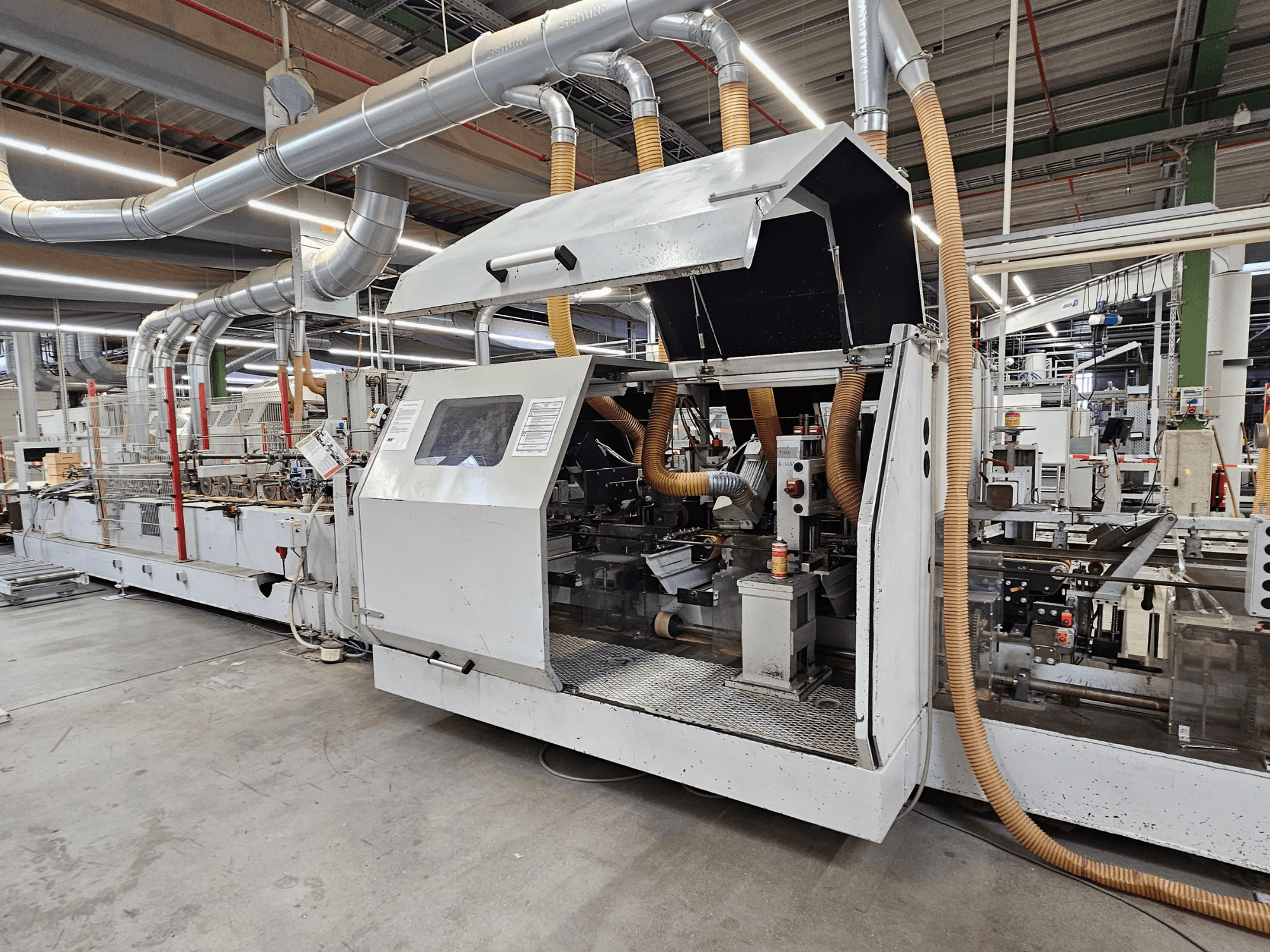 Bordatrice HOMAG FG63 in fabbrica, vista laterale che mostra i componenti operativi e il sistema di aspirazione della polvere.