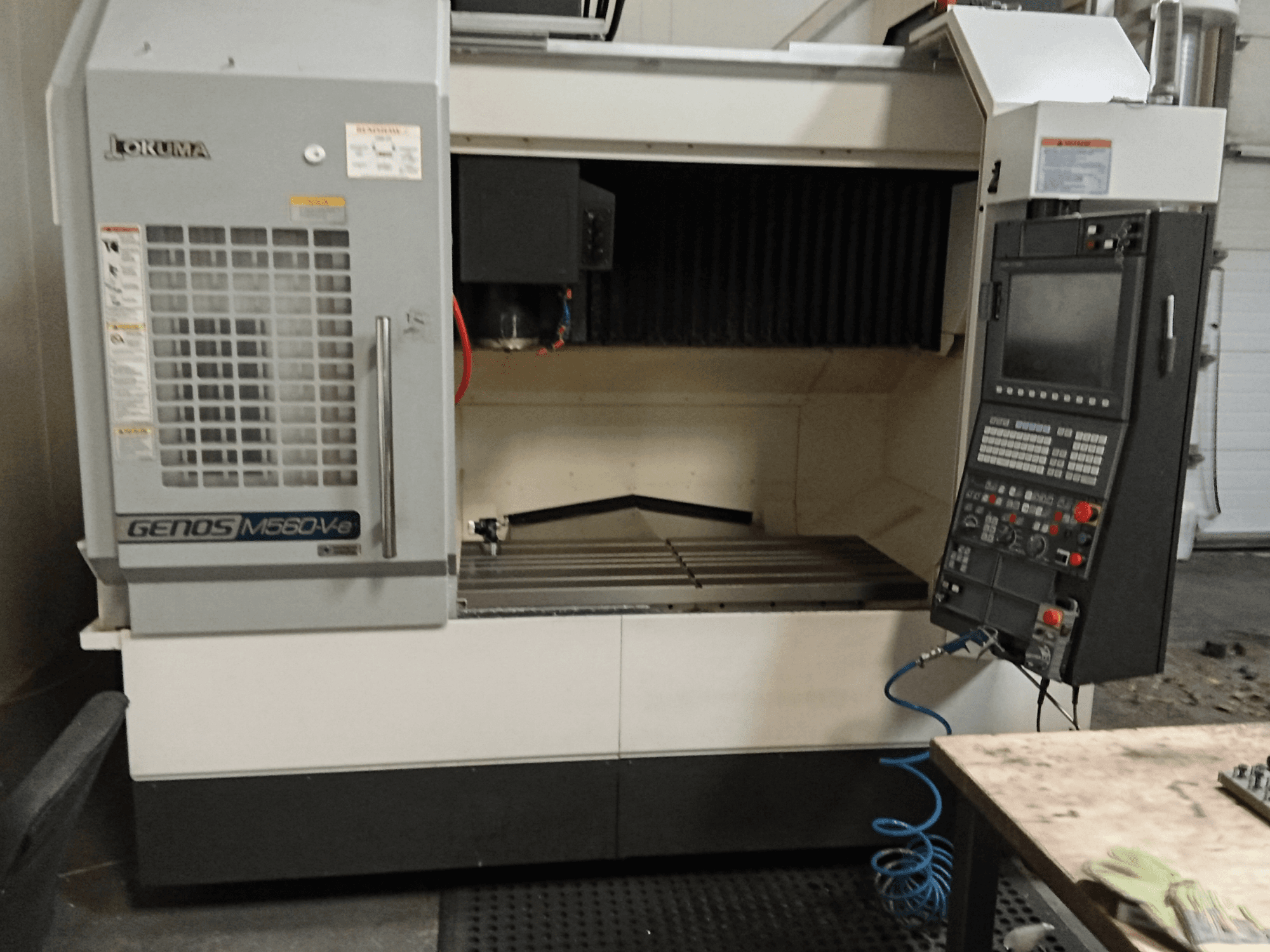 Okuma GENOS M560-V, vista frontale di un centro di lavoro verticale con pannello di controllo, interfaccia CNC e area di taglio visibile.
