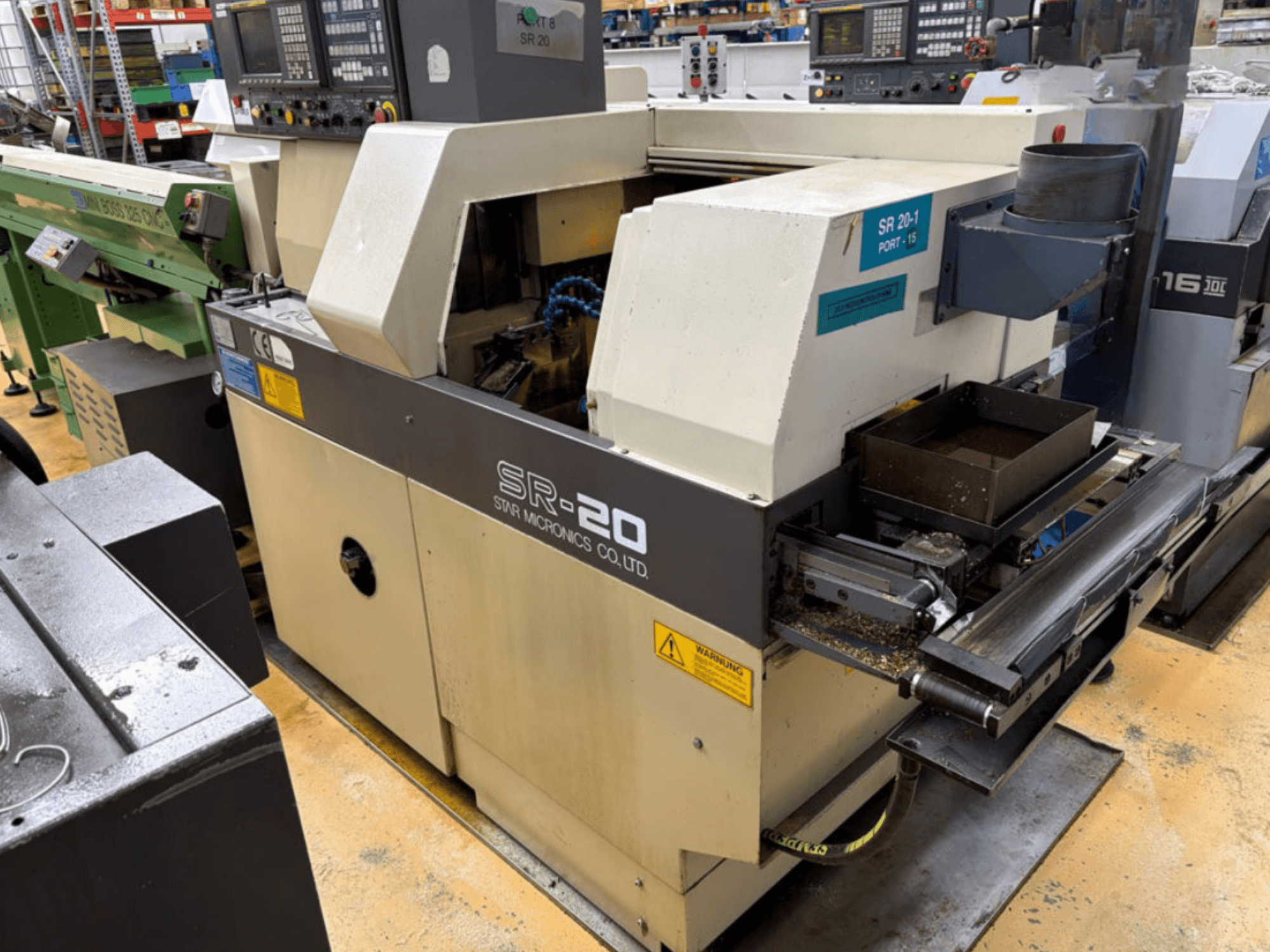 Tornio di tipo svizzero STAR MICRONICS SR20 visto di profilo, con pannello di controllo e zona di lavorazione con trucioli.