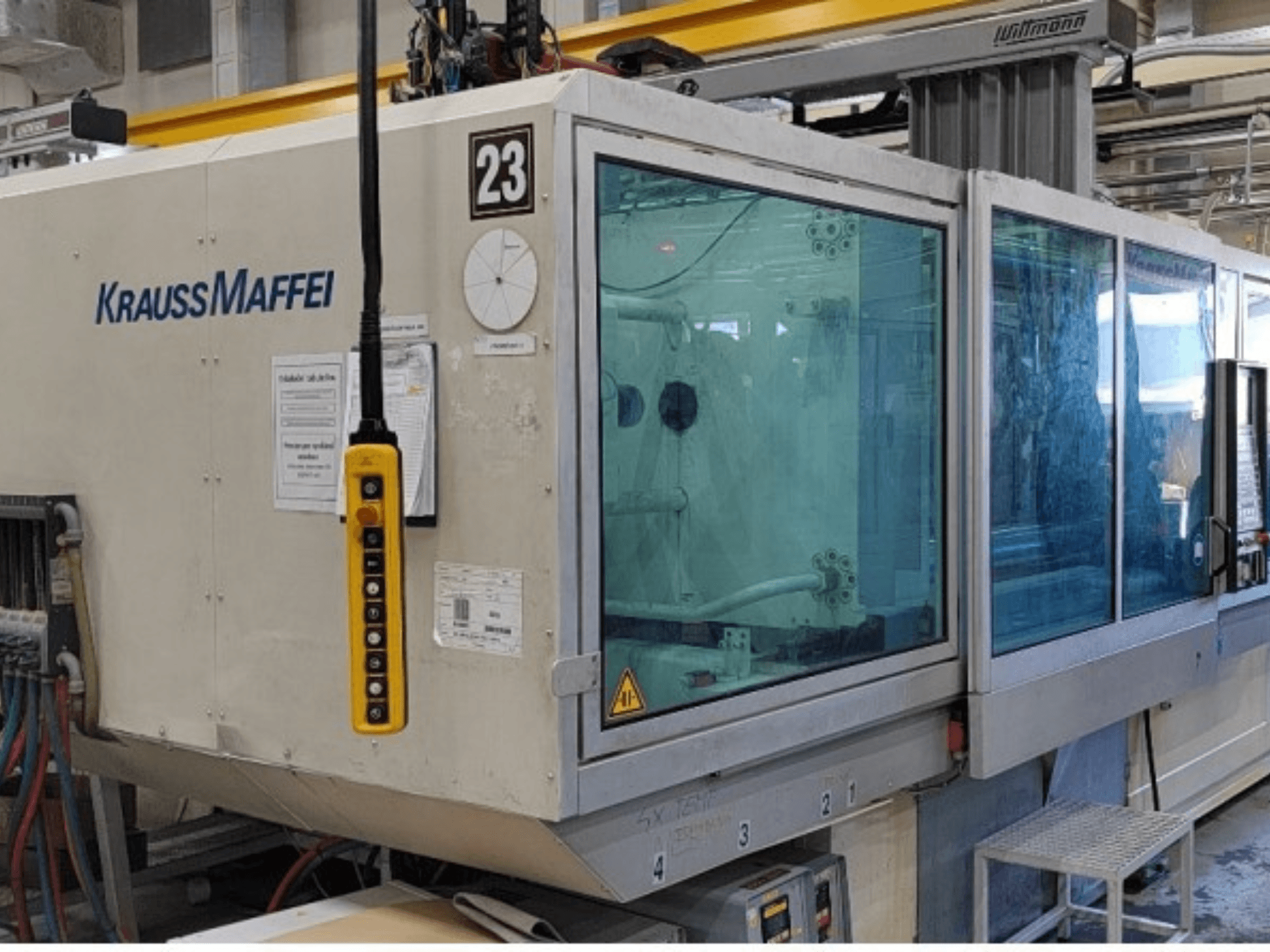 Pressa a iniezione idraulica Krauss Maffei KM 350-1900 C2, vista frontale che mostra il pannello di controllo e la cabina di sicurezza trasparente.