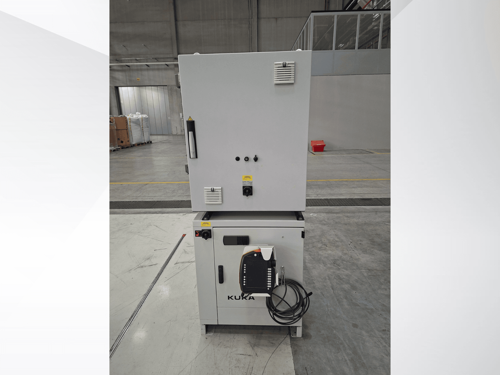 Controller del braccio robotico KUKA KR 90 R2700 PRO C4 FLR, vista frontale che mostra il pannello di controllo e le etichette di sicurezza in un ampio magazzino.
