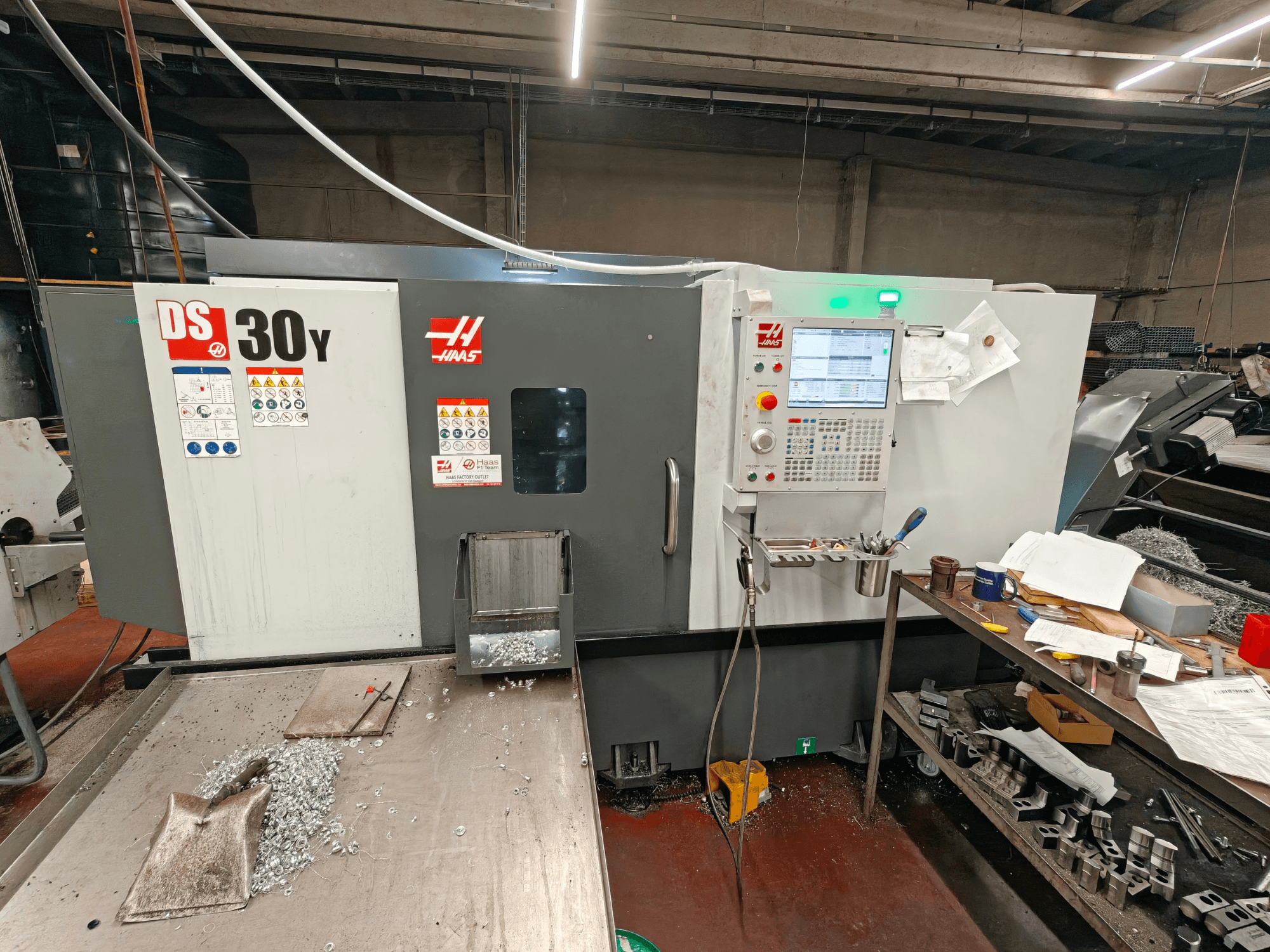 Tornio orizzontale HAAS DS30Y in un'officina, vista frontale che mostra il pannello di controllo e i trucioli metallici sulla superficie.