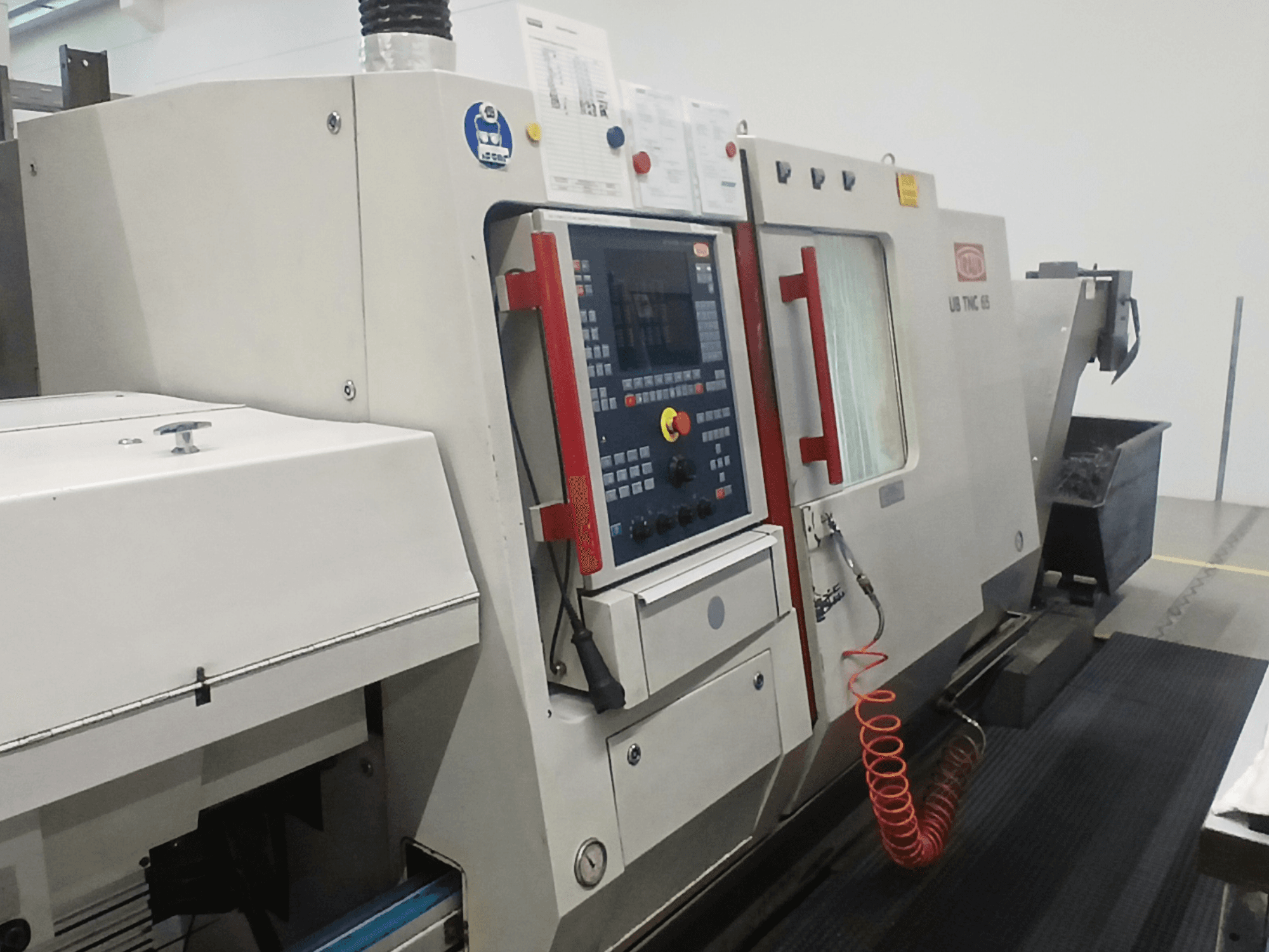 Tornio orizzontale TRAUB TNC65 DG, vista frontale, con pannello di controllo e utensili, ideale per lavorazioni di precisione.
