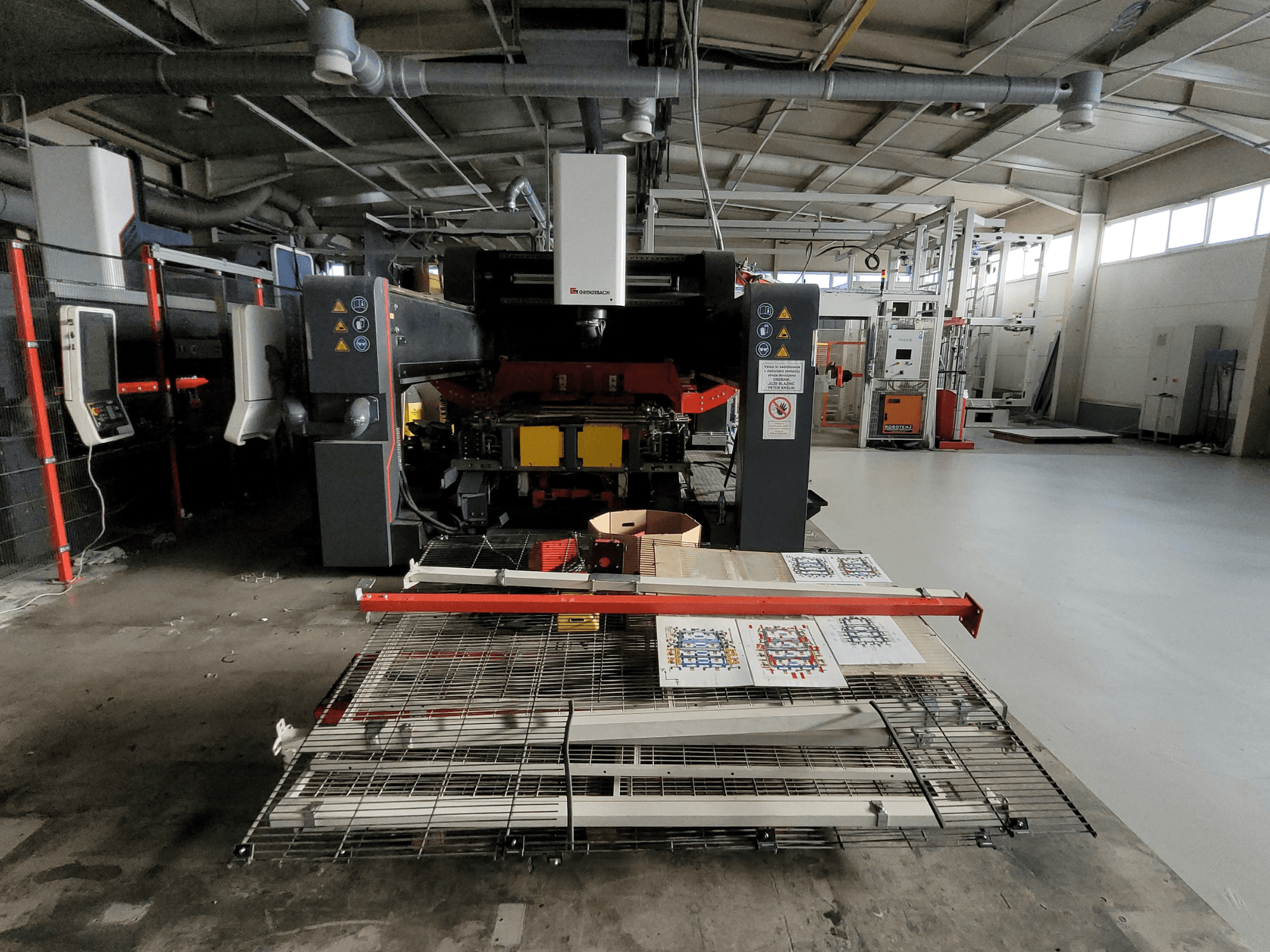 La macchina FSW DSM 2400 di GRENZEBACH, vista frontale nella configurazione di fabbrica, mostra l'allestimento di lavorazione con materiali stampati e attrezzature.