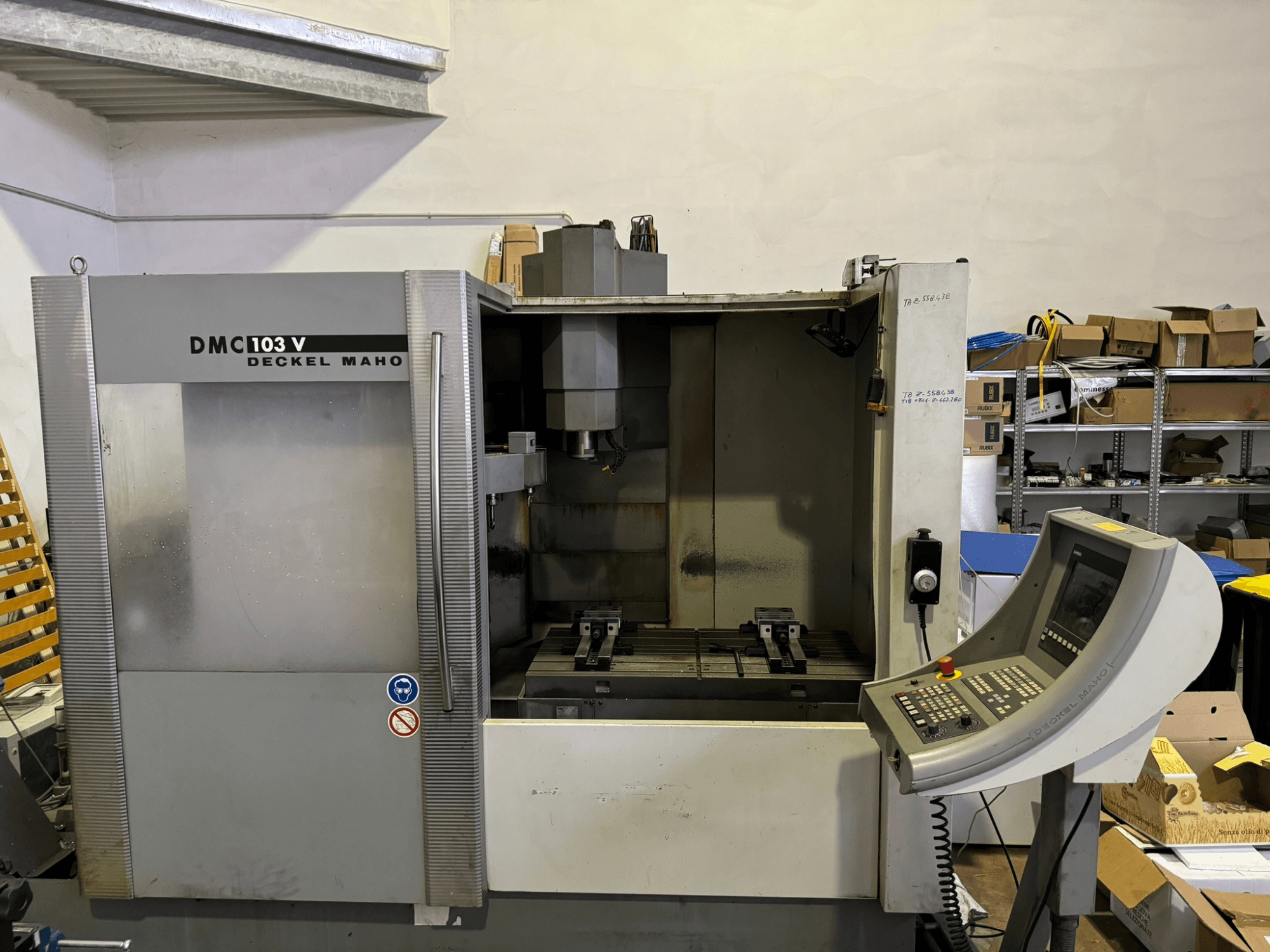 Fresatrice DMC 103 V Deckel Maho, vista frontale, con pannello operativo, parti metalliche e area di stoccaggio sullo sfondo.