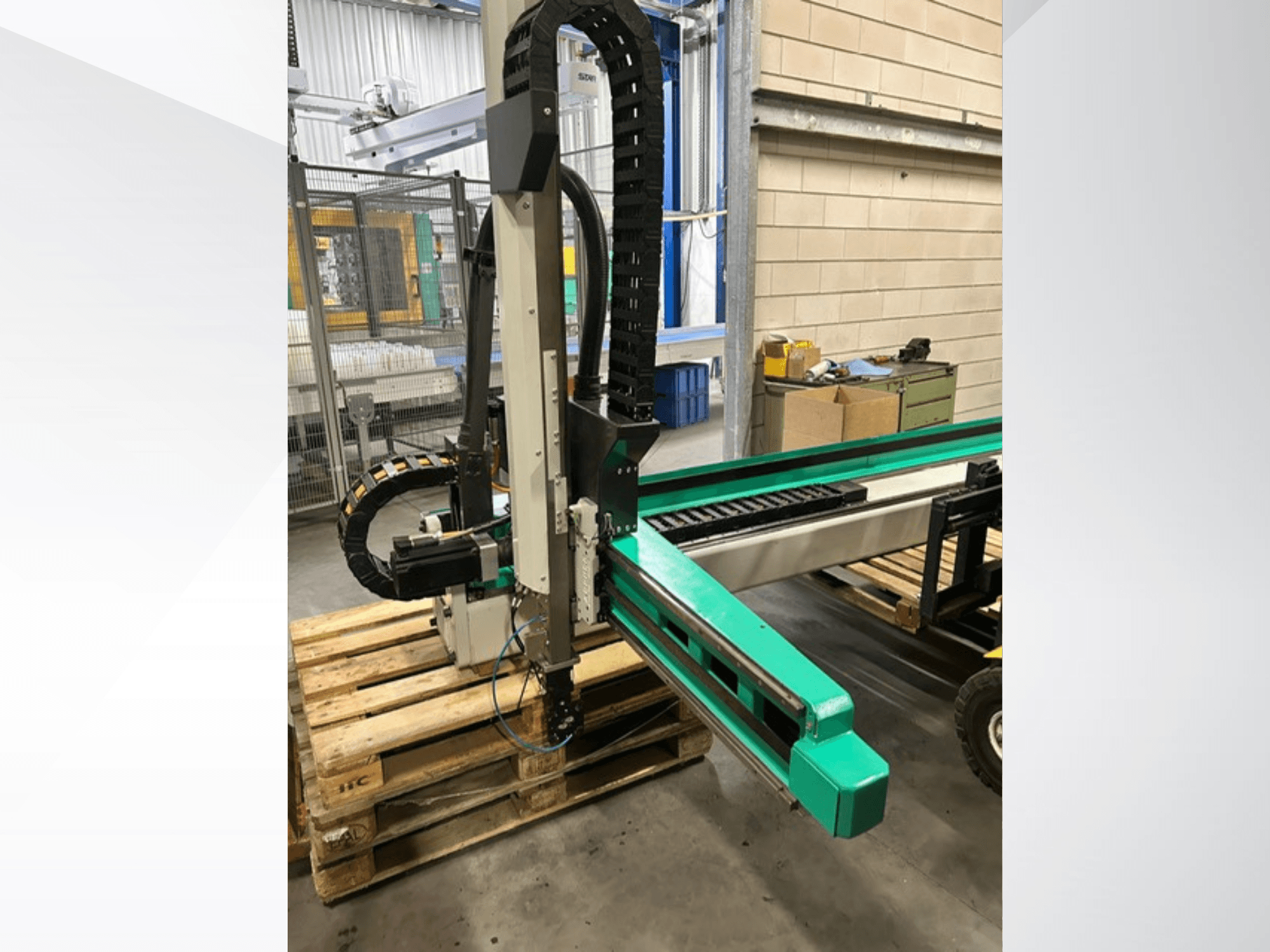 Arburg Multilift Select 15kg quer, vista laterale del sistema di movimentazione dei pezzi su pallet di legno, che mostra il braccio robotico e i componenti di controllo.