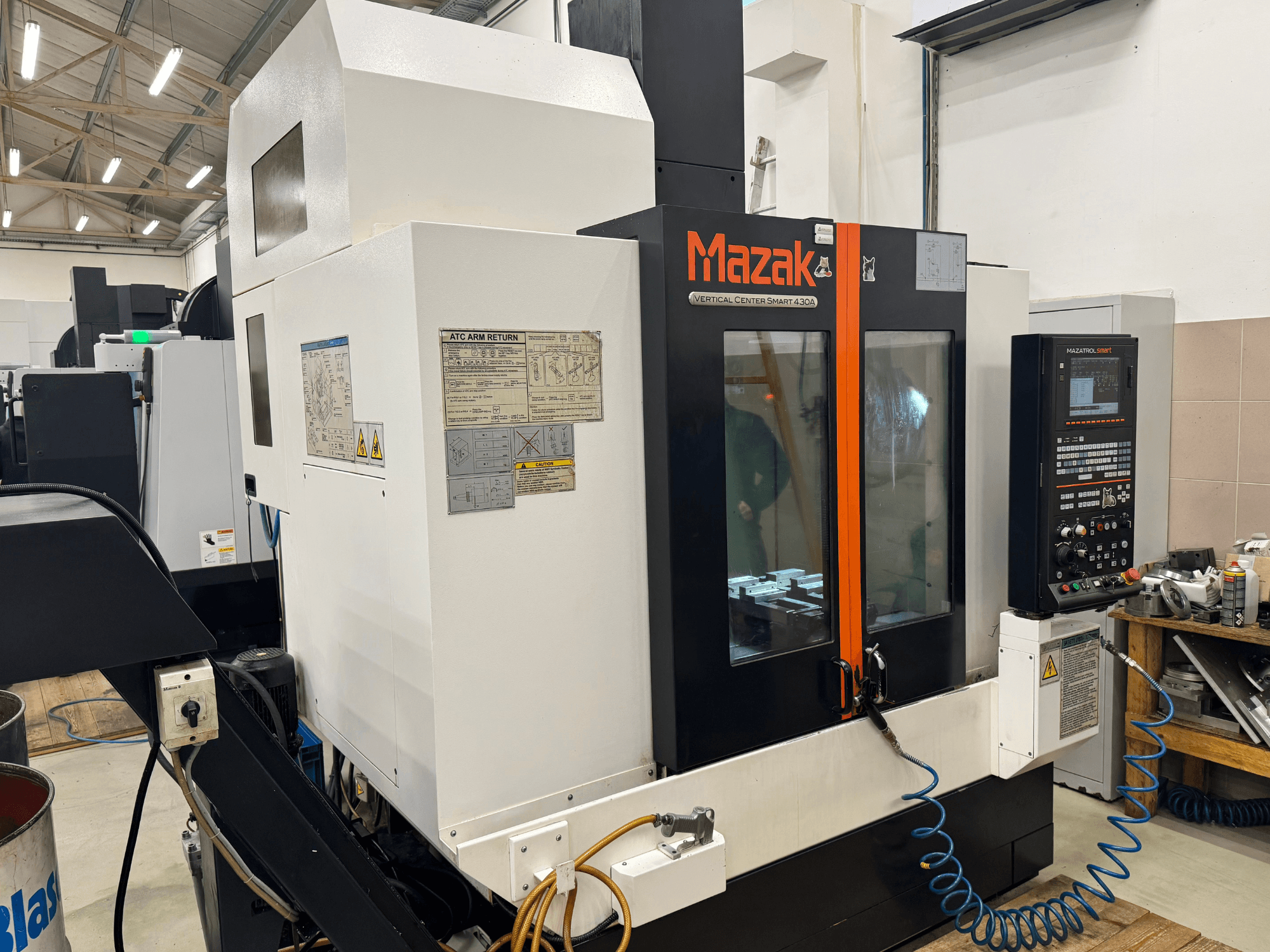 Mazak Vertical Center Smart 430A, vista frontale; fresatrice CNC con pannello di controllo, involucro trasparente e portautensili visibili.