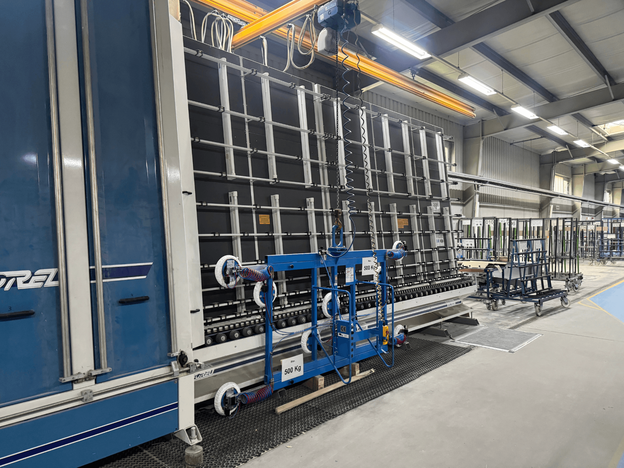 Attrezzatura industriale di Drel, caratterizzata da un grande telaio e da un meccanismo di sollevamento, vista lateralmente in un ambiente industriale.