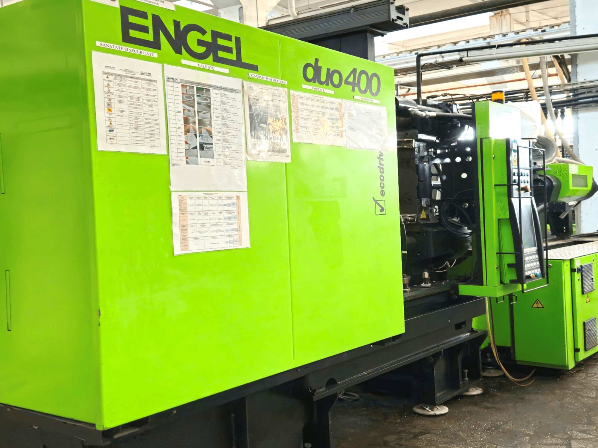 Macchina di stampaggio a iniezione ENGEL duo 400 verde, vista frontale, con pannello di controllo e documentazione di sicurezza all'esterno.