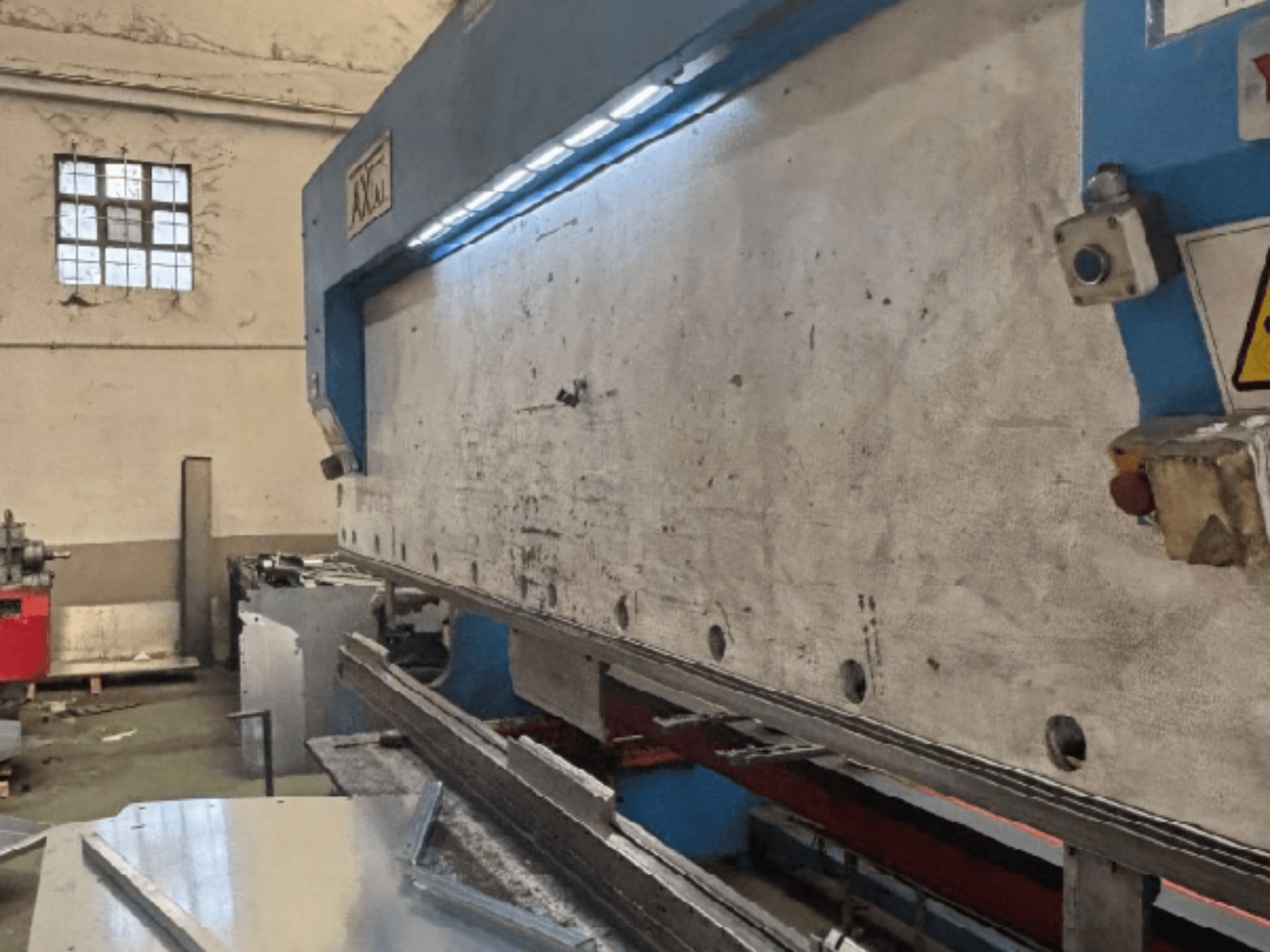 Sistema di movimentazione pallet Axial PHS-W-124 in un'officina, vista laterale che mostra la superficie di lavoro e i dettagli del pannello di controllo.