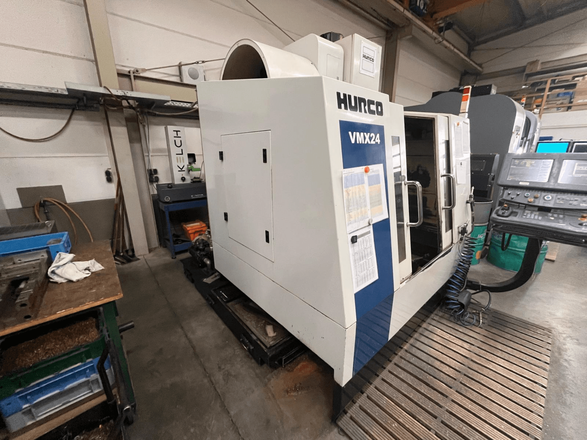 Macchina CNC Hurco VMX24 in un'officina, vista frontale; presenta un pannello di controllo e una porta di accesso aperta.