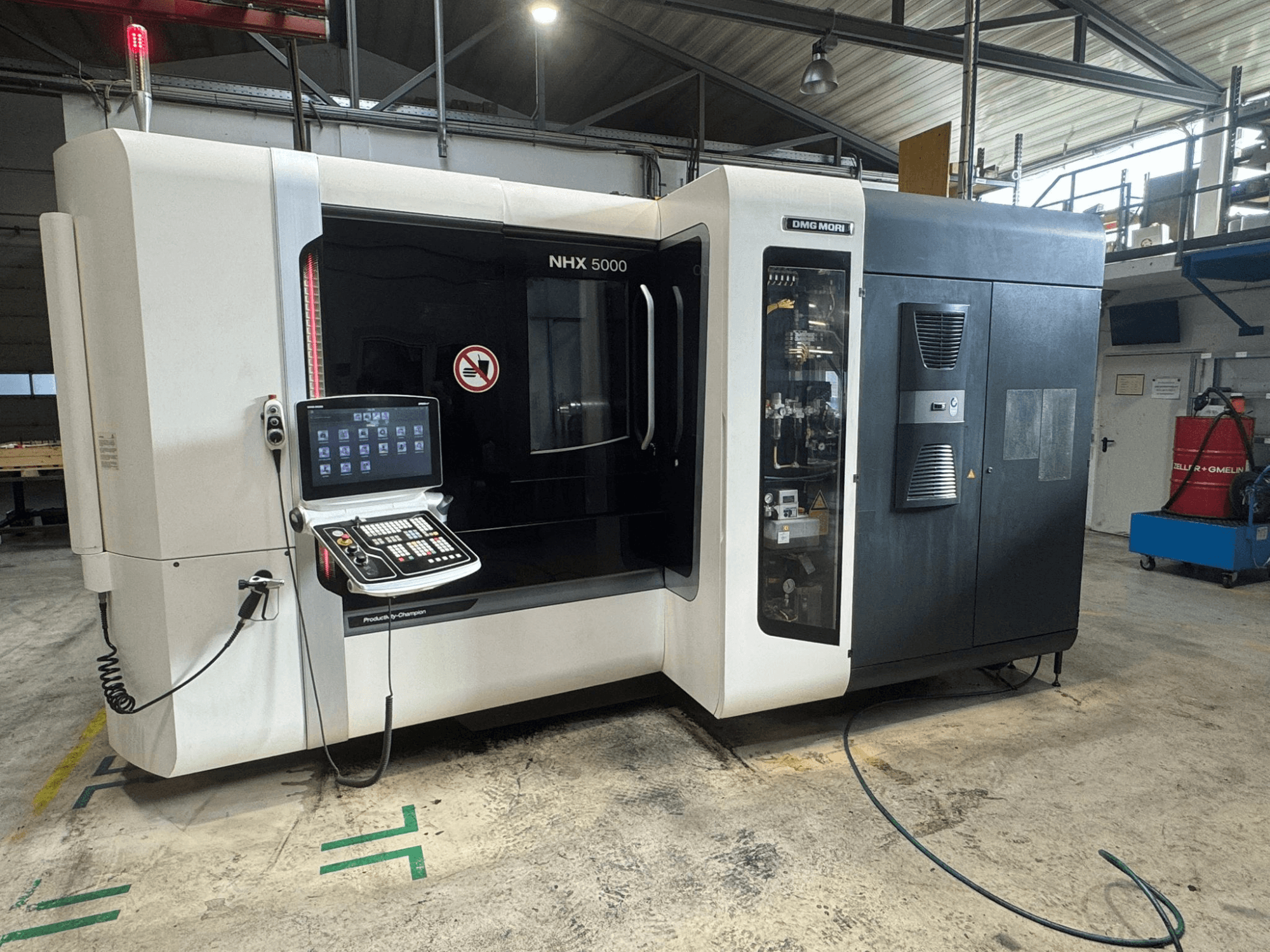 Centro di lavoro orizzontale DMG MORI NHX 5000, vista frontale con pannello di controllo visibile e indicatori di sicurezza.
