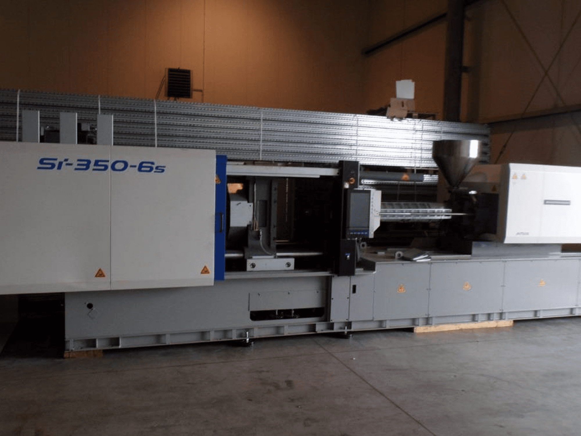 Macchina di stampaggio a iniezione Si-350-6s in vista laterale, con tramoggia e pannello di controllo, situata in un ampio ambiente industriale.