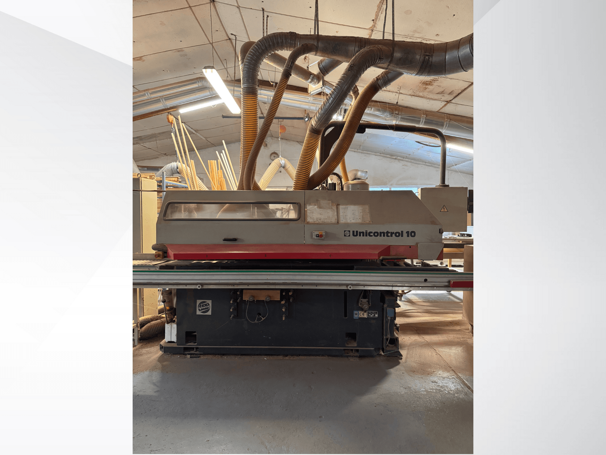 Vista frontale di una macchina Unicontrol 10 per la lavorazione del legno, con tubi di aspirazione della polvere e comandi operativi.