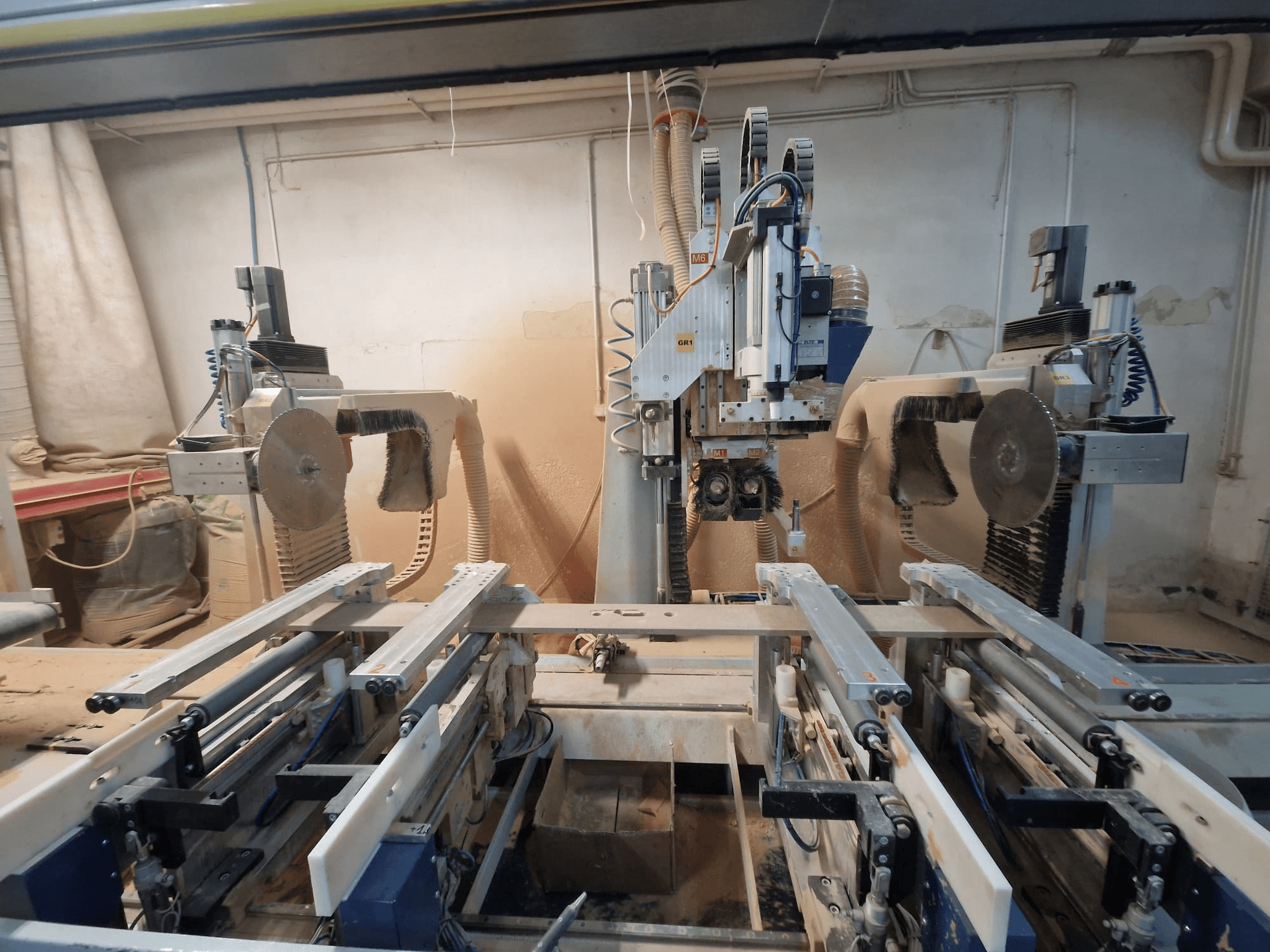 Macchina CNC con doppia lama e rotaia, vista dal davanti. Sistemi di aspirazione delle polveri visibili, adatti alla lavorazione del legno.