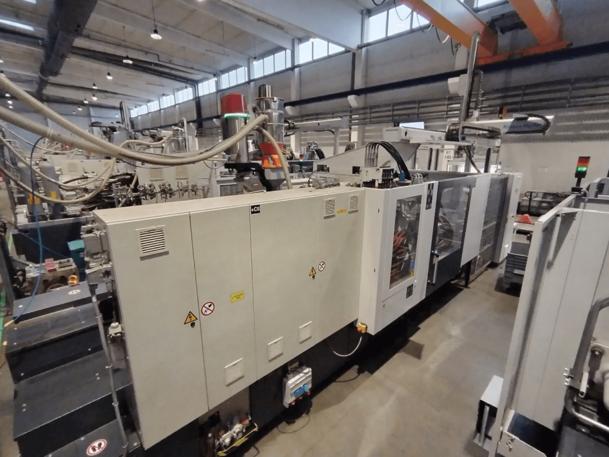 Macchina industriale per lo stampaggio a iniezione vista di lato, con pannello di controllo e avvisi di sicurezza. Marca: Sconosciuto.