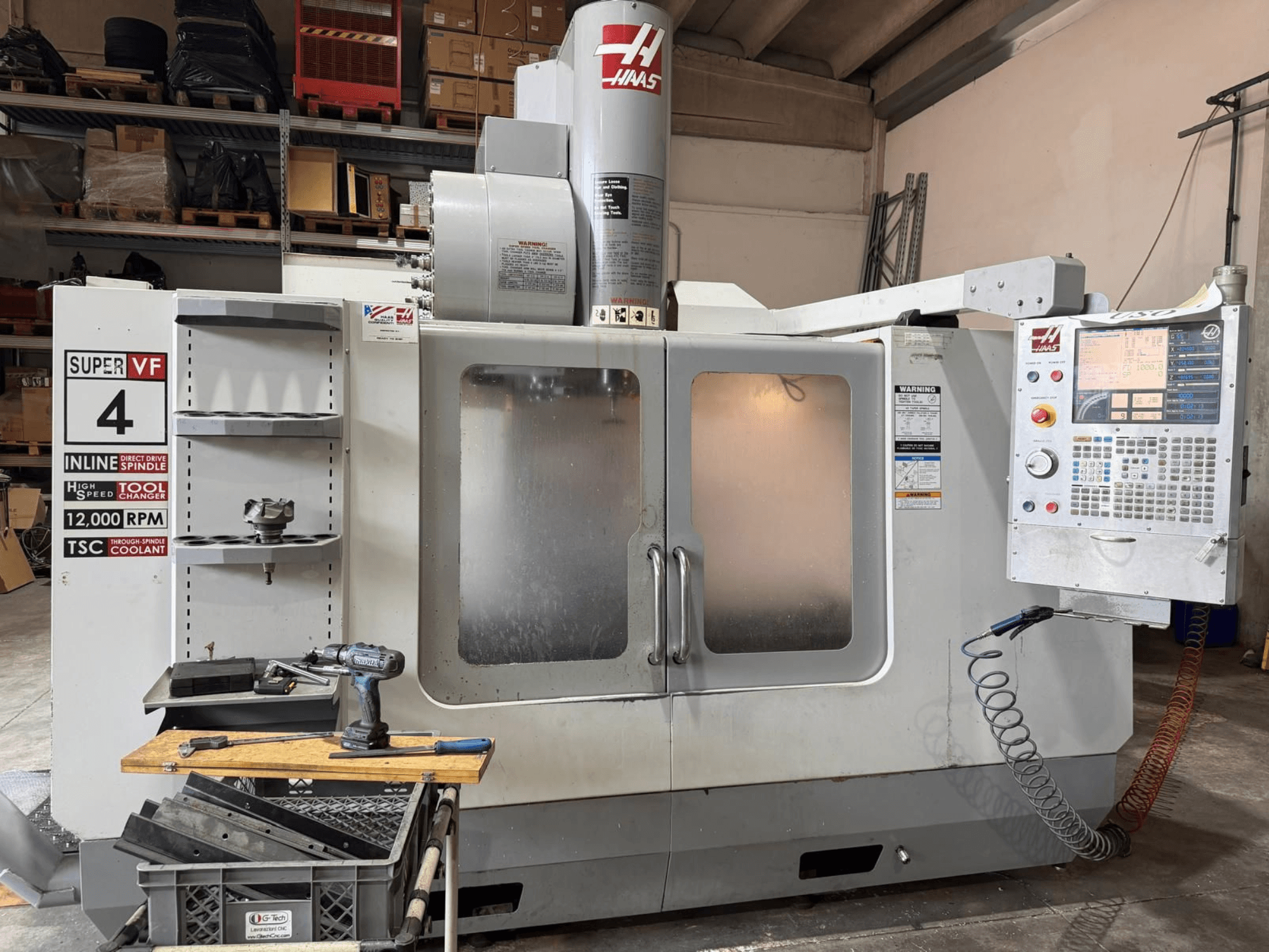 Vista frontale del centro di lavorazione verticale HAAS VF-4SSHE con pannello di comando, portautensili e mandrino da 12.000 giri/min; macchina ad alta velocità e precisione.