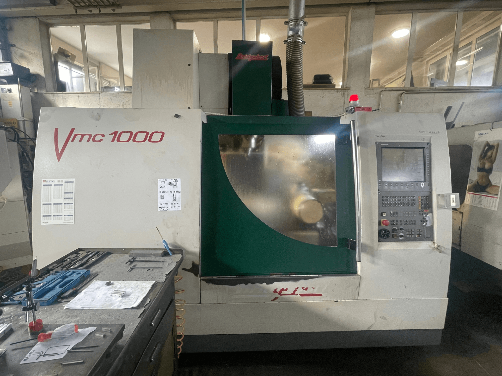 Centro di lavorazione verticale Bridgeport VMC 1000/30, vista frontale, con pannello di controllo e corpo principale, e utensili nelle vicinanze.