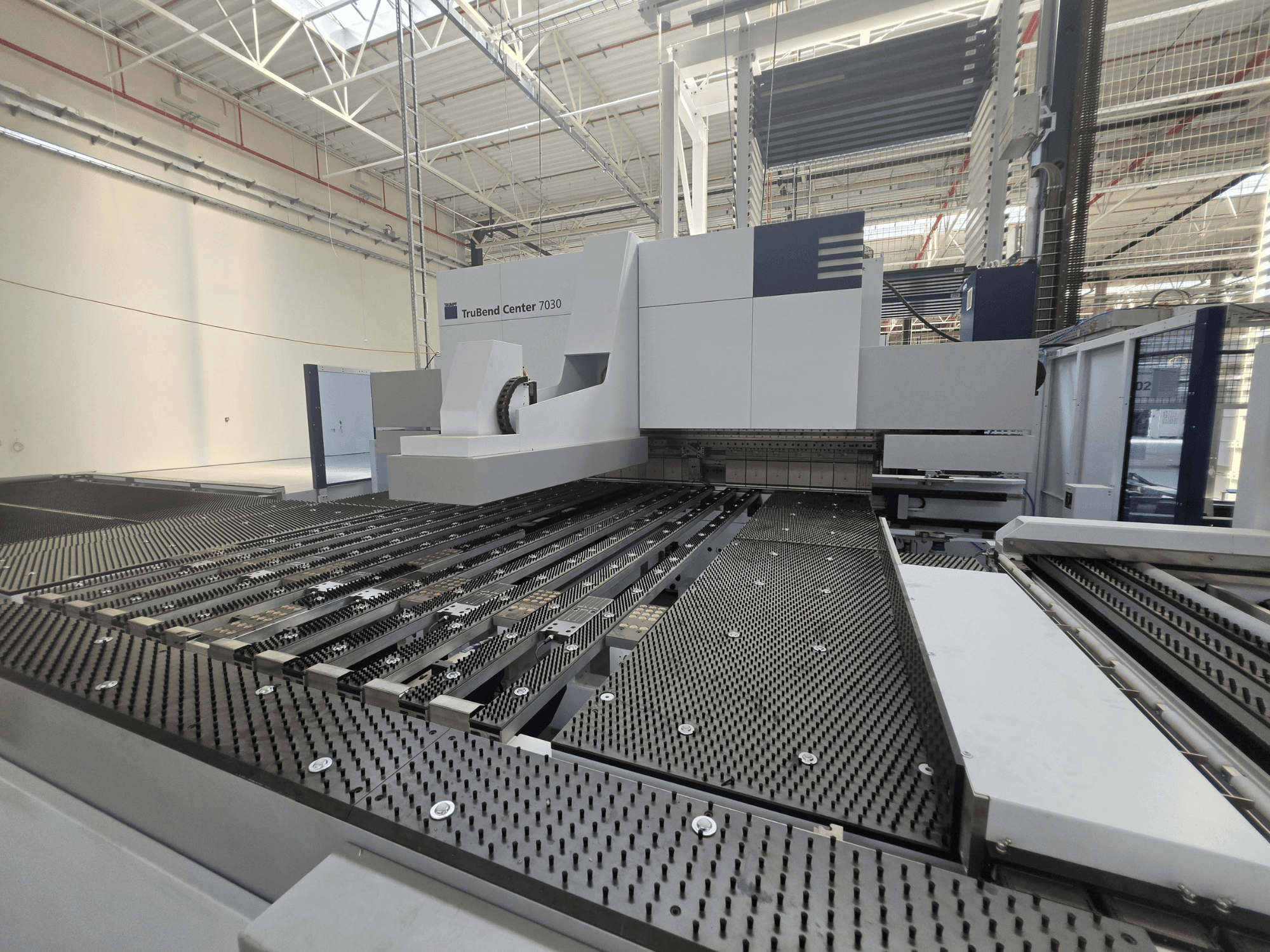 Piegatrici TRUMPF TruBend Center 7030 in un ambiente di produzione, vista frontale che mostra il complesso piano di lavoro e il braccio di piegatura.