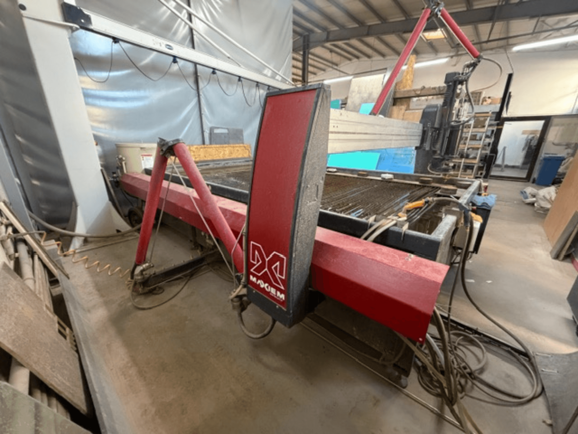 Macchina da taglio a getto d'acqua rossa del marchio X, vista di lato, che mostra i componenti meccanici e i dettagli delle tubazioni.