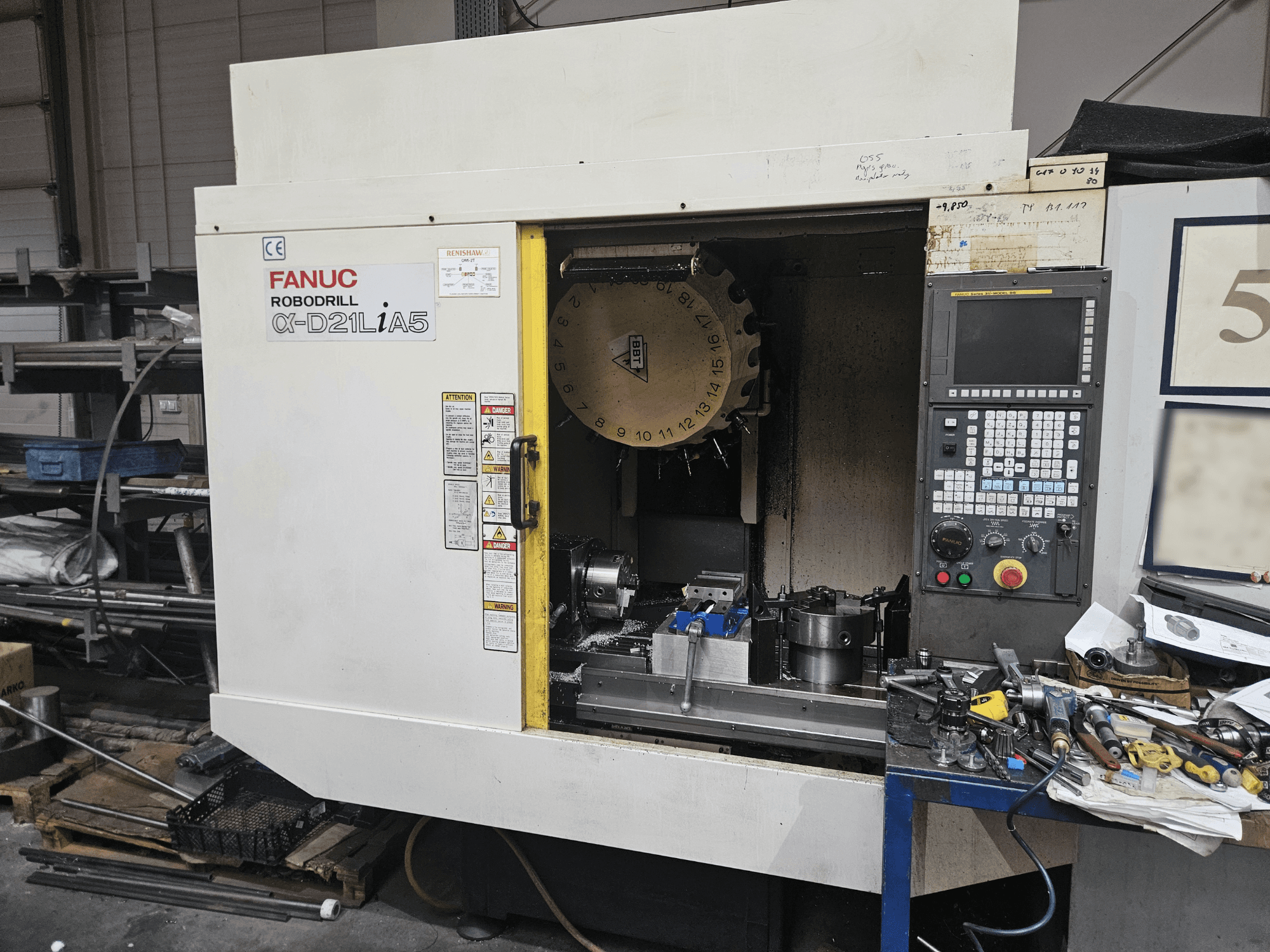 FANUC Robodrill α-D21LiA5, vista frontale che mostra il portautensili e il pannello di controllo, circondato da utensili e attrezzature in un'officina.