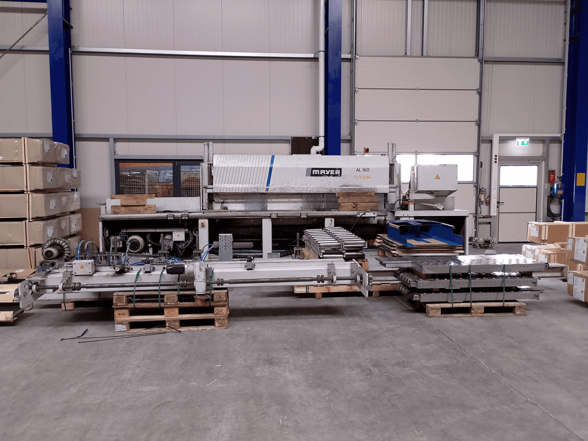 La sezionatrice MAYER AL160 in un magazzino con pallet, che mostra il piano di taglio e i componenti della macchina, vista frontale.