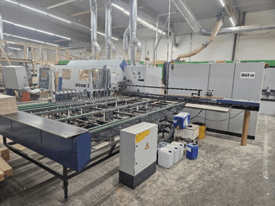Vista laterale di una macchina CNC Unimat 2 in un'officina, con nastri trasportatori e componenti tecnici con unità Max 08 visibile.