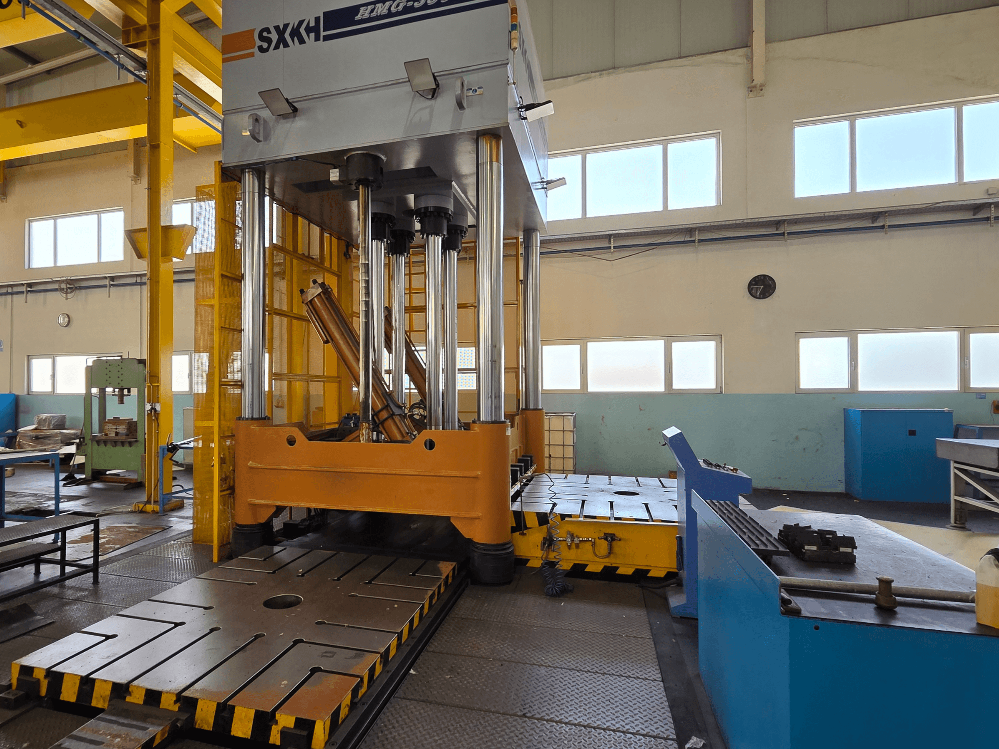 Vista frontale della pressa idraulica SXKH HMG-300JM, dotata di grandi cilindri di pressatura e di un robusto basamento in un ambiente industriale.