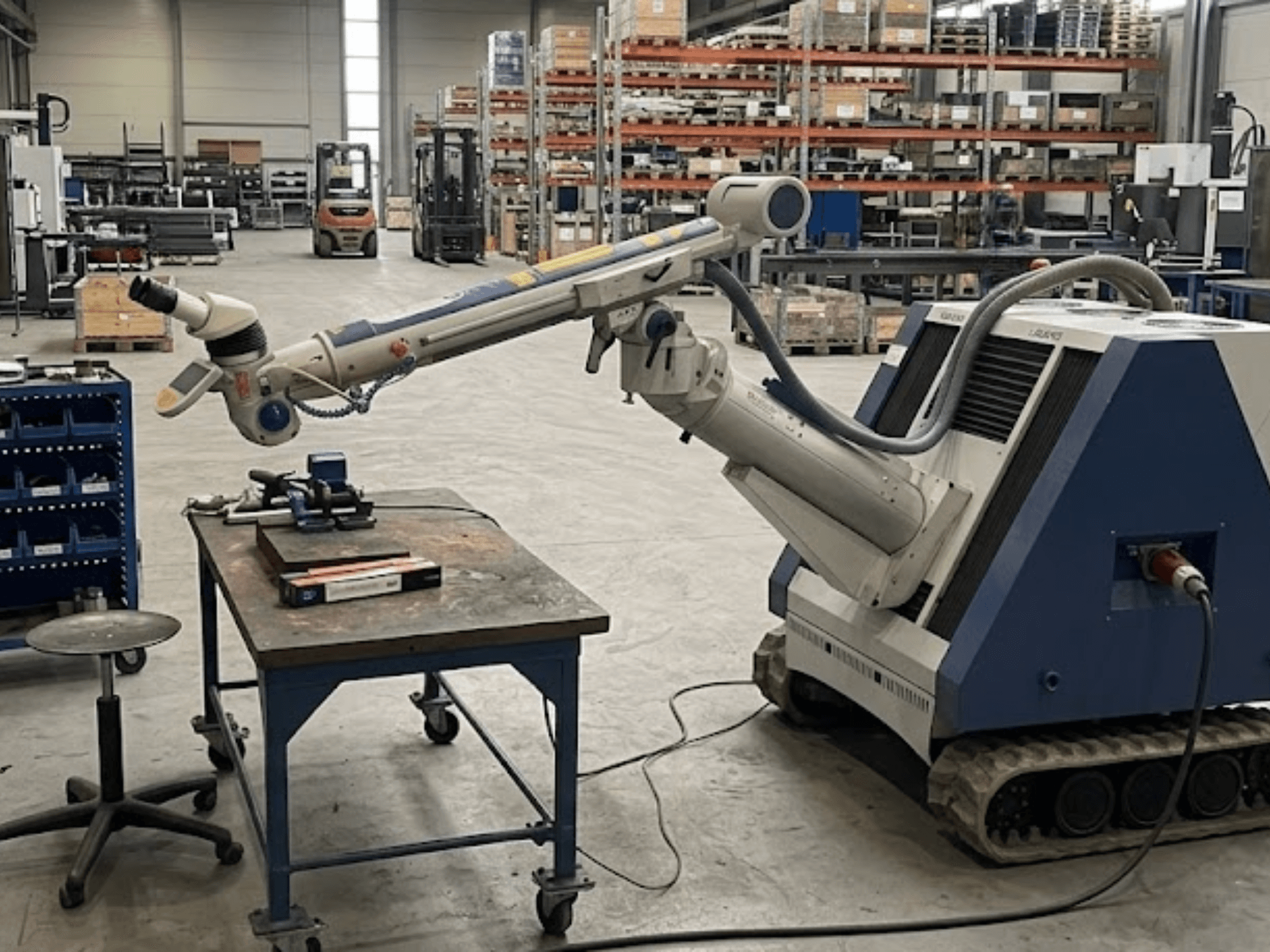 Macchina utensile ALPHA LASER ALFlak300 M in un'officina con braccio robotico; vista frontale che mostra la configurazione di precisione sul piano di lavoro.