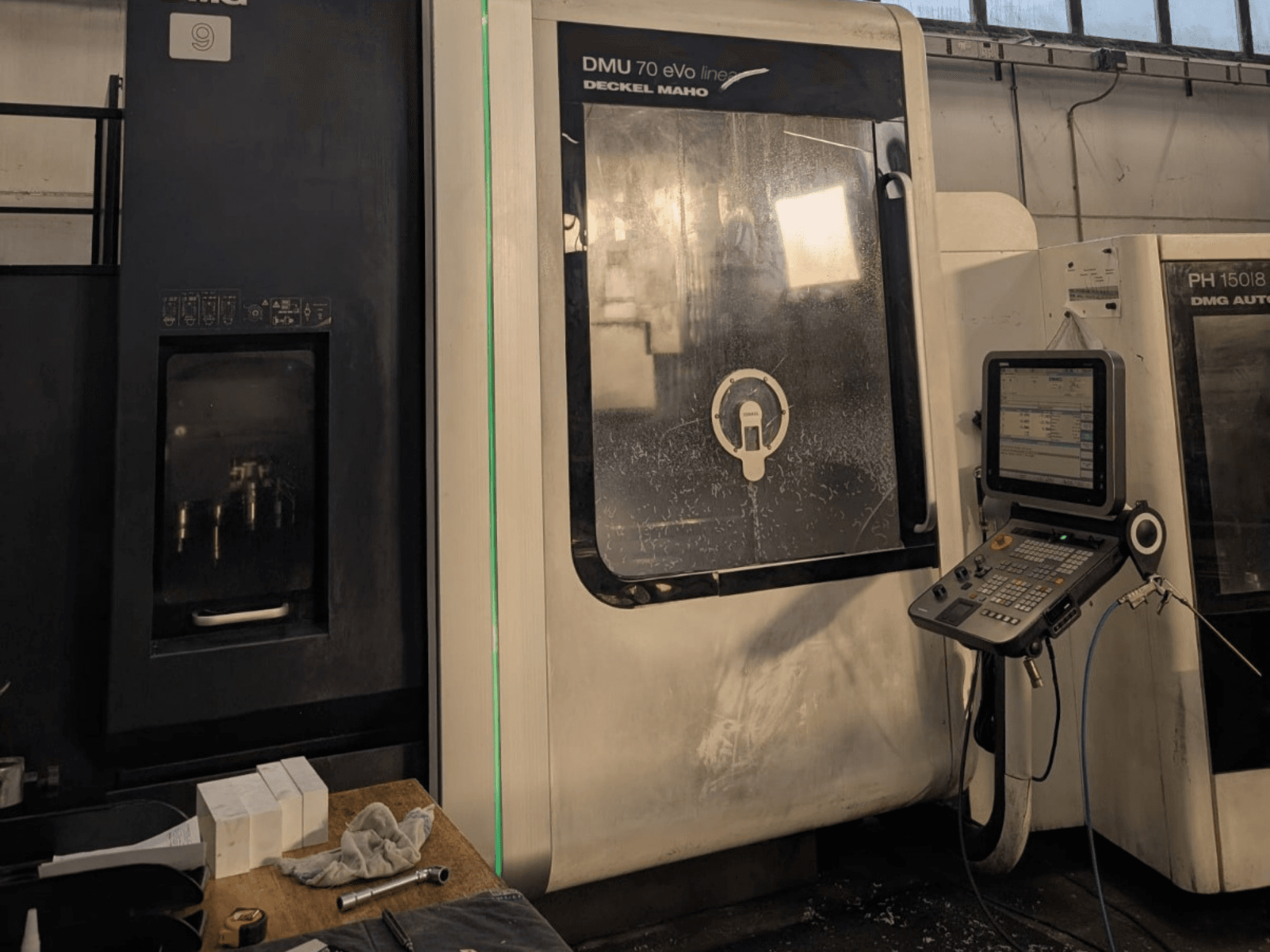 Centro di lavoro verticale lineare DMG DECKEL MAHO DMU 70 EVO, vista frontale con pannello di controllo, utensili e area di lavoro visibili.