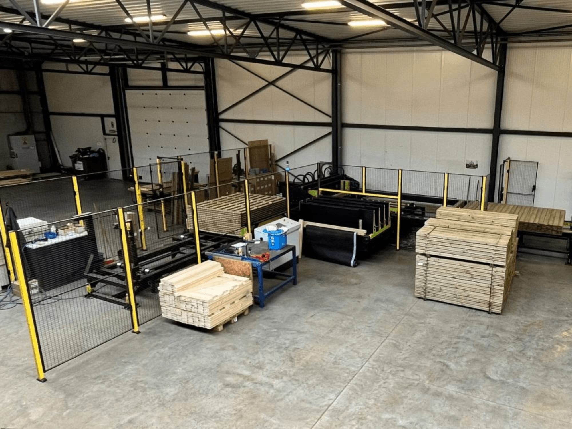 Linea di produzione completa (ISM ATM-01) per il legno, vista dall'alto, con macchinari, pallet di legno e recinzioni di sicurezza.