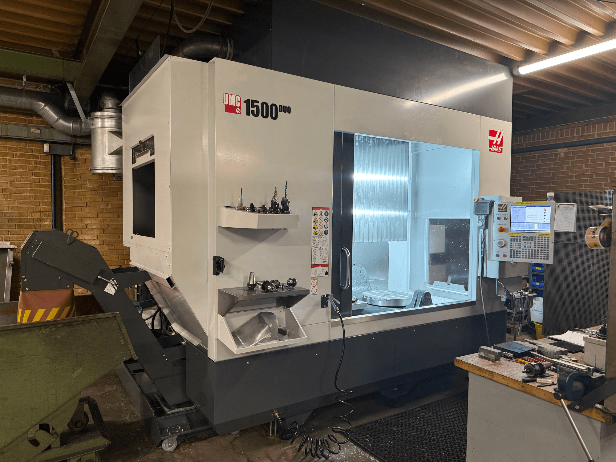 Macchina CNC Haas UMC 1500DUO, vista frontale, con ampia finestra, pannello di controllo e portautensili su un ripiano.